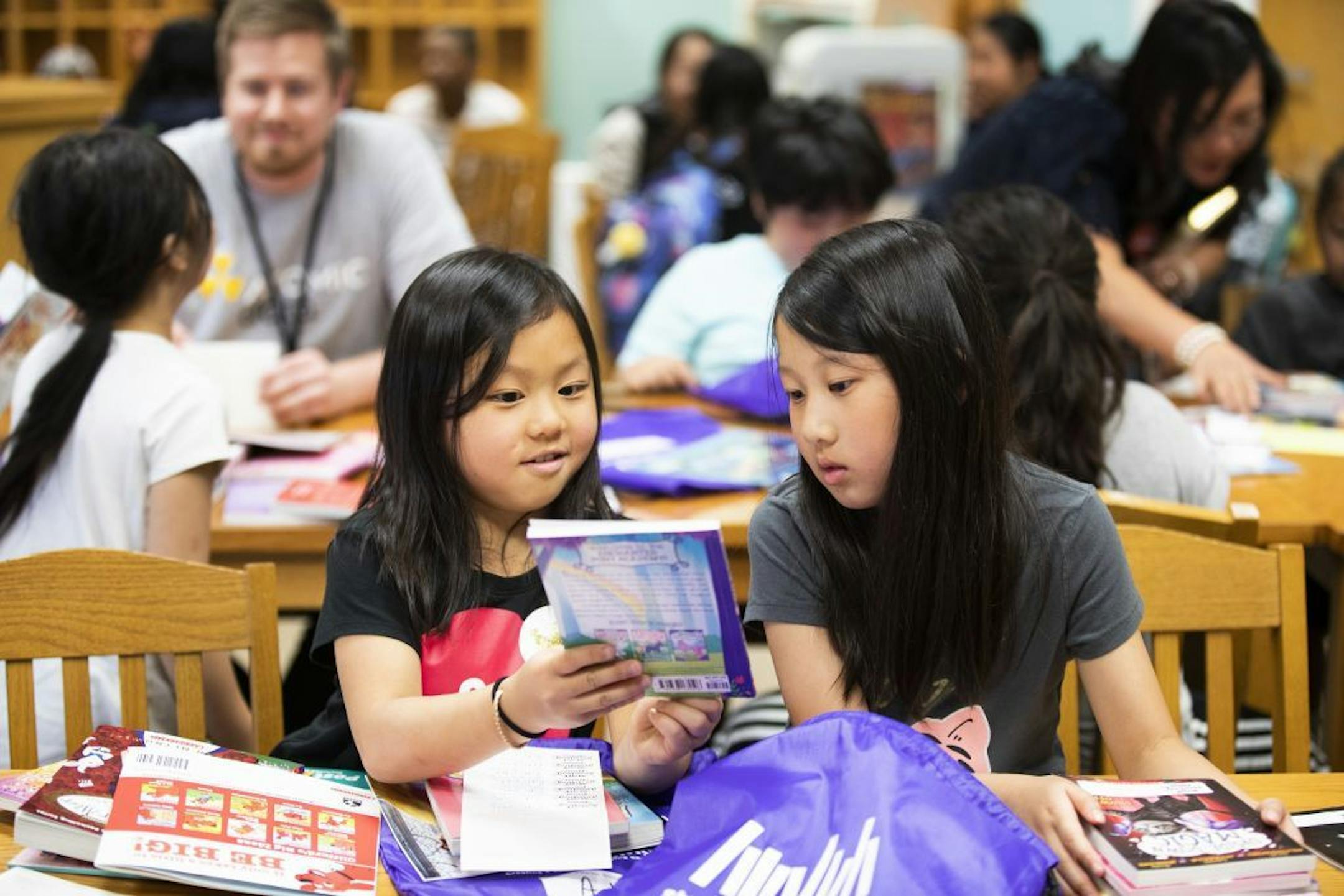 Second graders Aaliyah Xiong, left, and Sarah Lor compare books after the book fair.