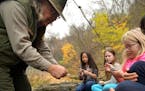 National Park Service Ranger Dave Wiggins instructs Lianna Remmen, a fifth grader from St. Paul's Heights Community School, how to build a campfire us