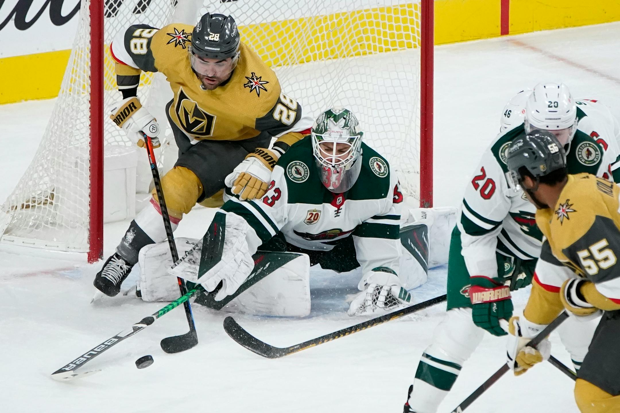Minnesota Wild goaltender Cam Talbot (33) knocks the puck away from Vegas Golden Knights left wing William Carrier (28) during the third period of an NHL hockey game Saturday, April 3, 2021, in Las Vegas. (AP Photo/John Locher)
