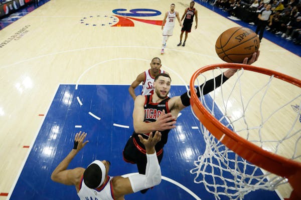 Chicago Bulls' Zach LaVine, center, goes up to shoot between Philadelphia 76ers' Tobias Harris