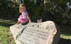 Hadley Kull, 2, climbs on the stone commemorating the site where Kaposia Indian remains were reburied in 1938 and again in 1958.