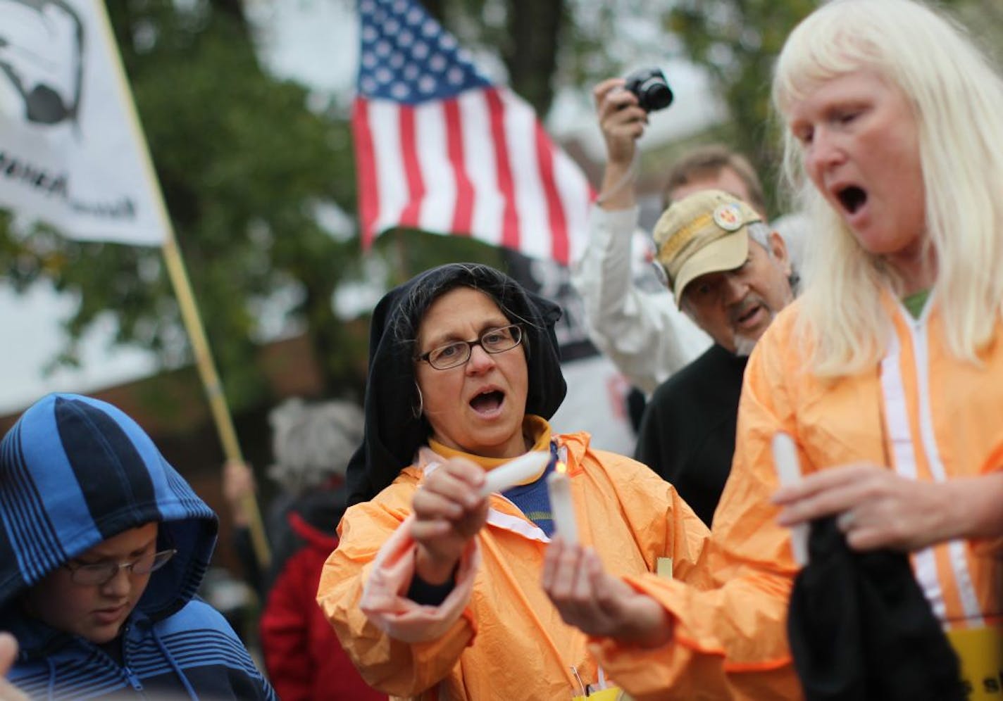 Protesters Coleen Rowley, of Apple Valley in black hood, and Kim Doss-Smith, of Minneapolis at right, sang "This little light of mine" as they lit candles outside a fundraiser by President George W. Bush at Beth El Synagogue in St. Louis Park, Minn., Wednesday, September 21, 2011.