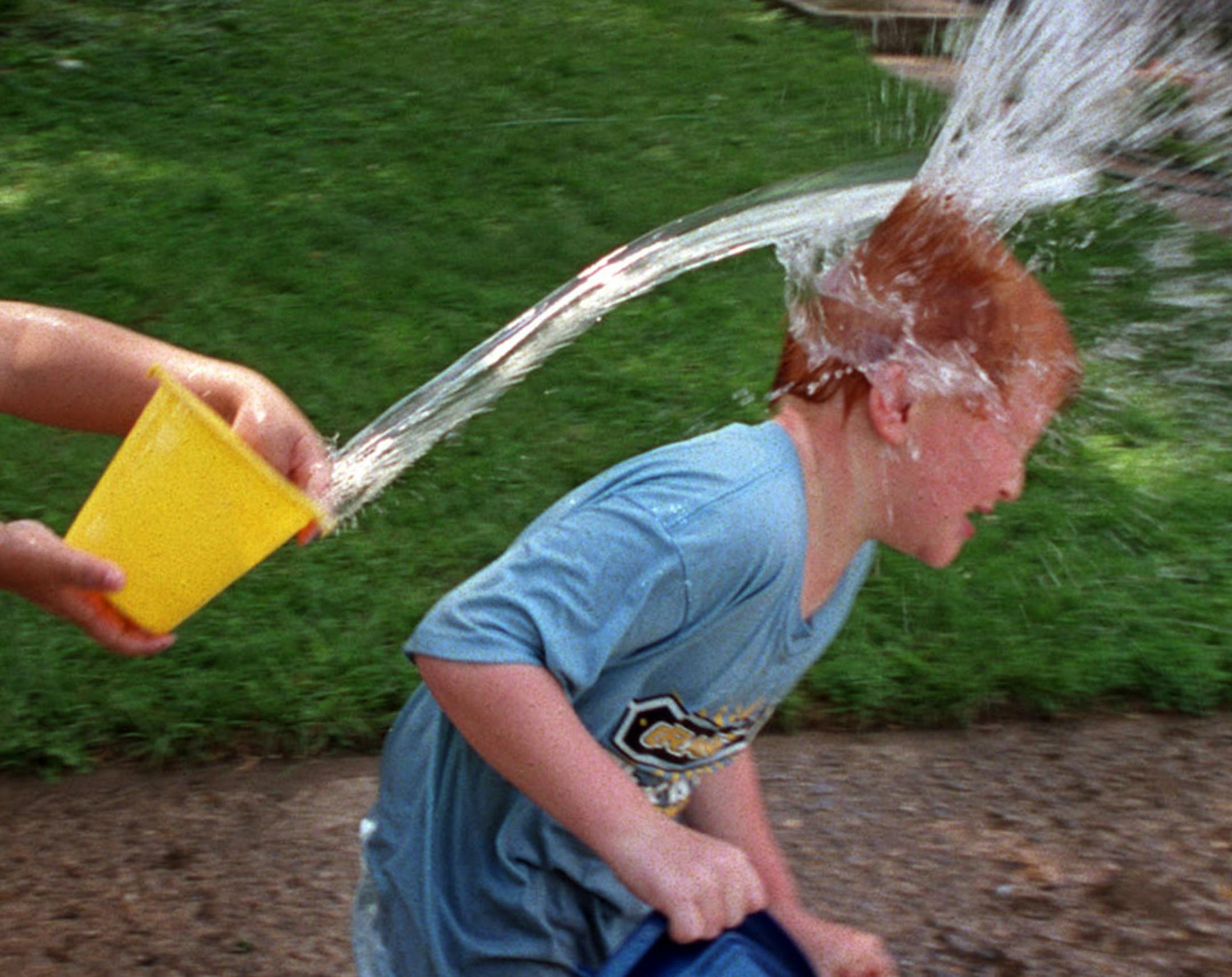 GENERAL INFORMATION: Wednesday, August, 1, 2001-Worhtington-A large influx of immigrants during the '90s is being felt throughout Worthington. IN THIS PHOTO: Dustin Dykema, 6, gets dosed with a bucket of water by his friend and neighbor, Tommy Sithad, 9, on a hot summer afternoon in Worthington. ORG XMIT: MIN2014031517031373