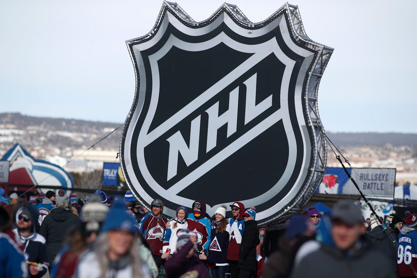 Fans pose below the NHL league logo at a display outside Falcon Stadium before an NHL Stadium Series outdoor game between the Los Angeles Kings and Colorado Avalanche