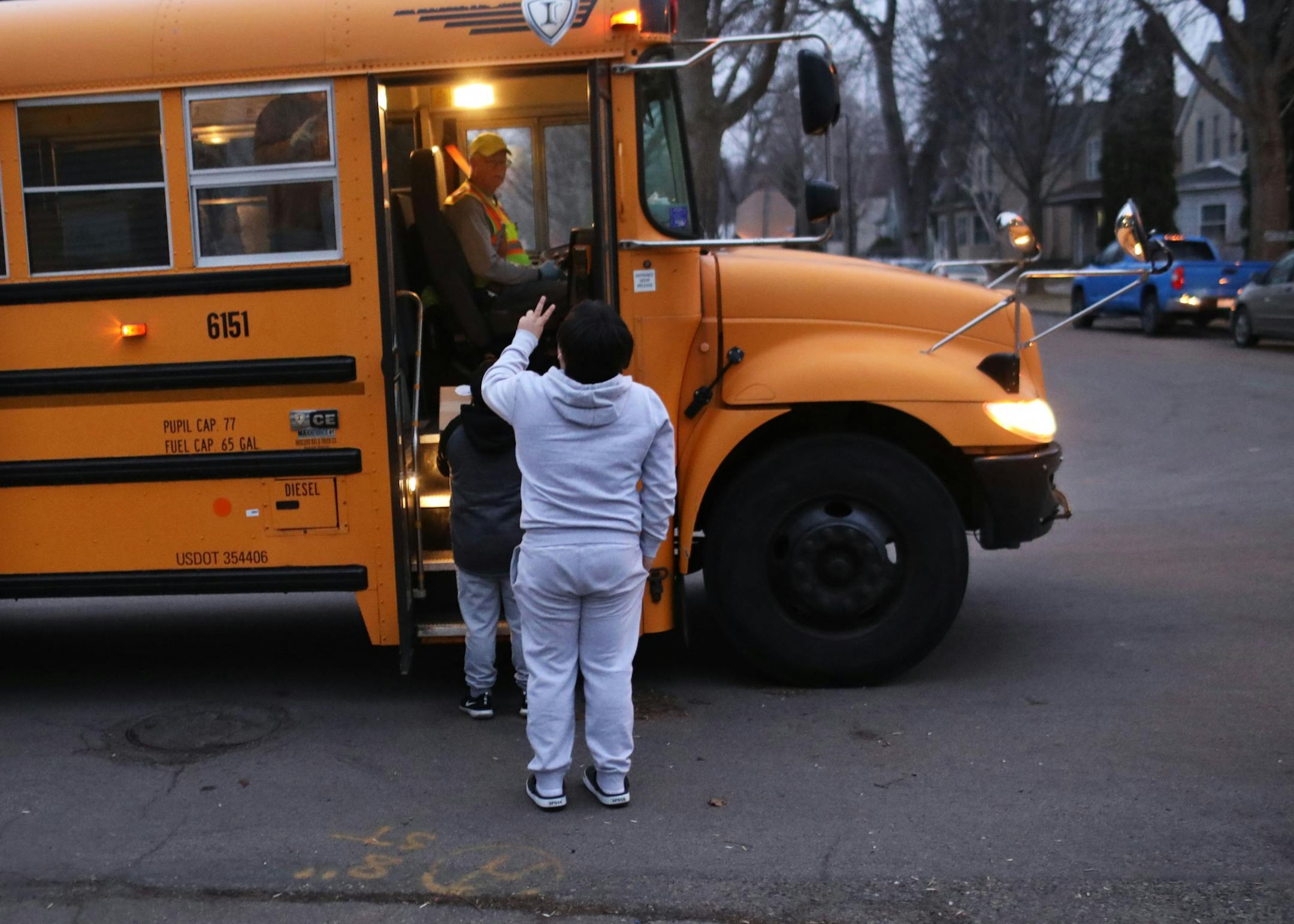 St. Paul school bus drivers and aides headed out a week's worth of breakfasts and lunches to families of students along their route Wednesday, March 25, 2020, in St. Paul, MN. Here, a father and son wait for boxes with meals to be handed out along the route.