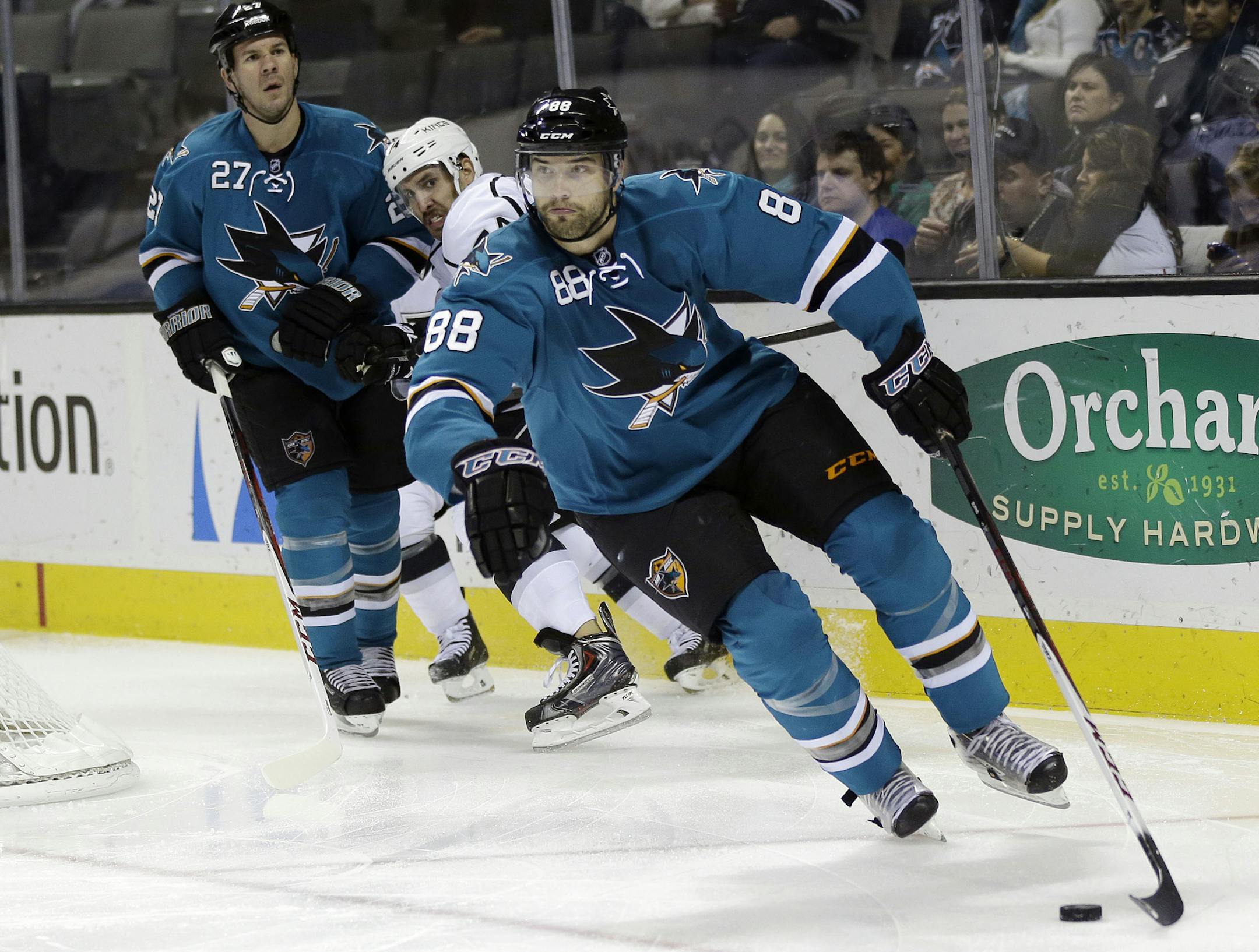 San Jose Sharks' Brent Burns (88) skates past Los Angeles Kings' Dwight King (74), center, and Sharks' Scott Hannan (27) during the second period of an NHL hockey game Wednesday, Nov. 27, 2013, in San Jose, Calif. (AP Photo/Marcio Jose Sanchez) ORG XMIT: SJA104