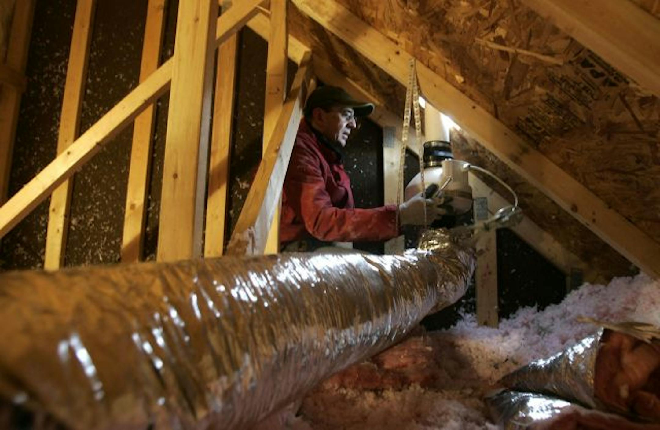 Mike Sommer, a radon mitigation installer for Advanced Radon Services LLC, installs a radon suction fan above a garage during radon mitigation of a home in Stillwater that was recently sold.