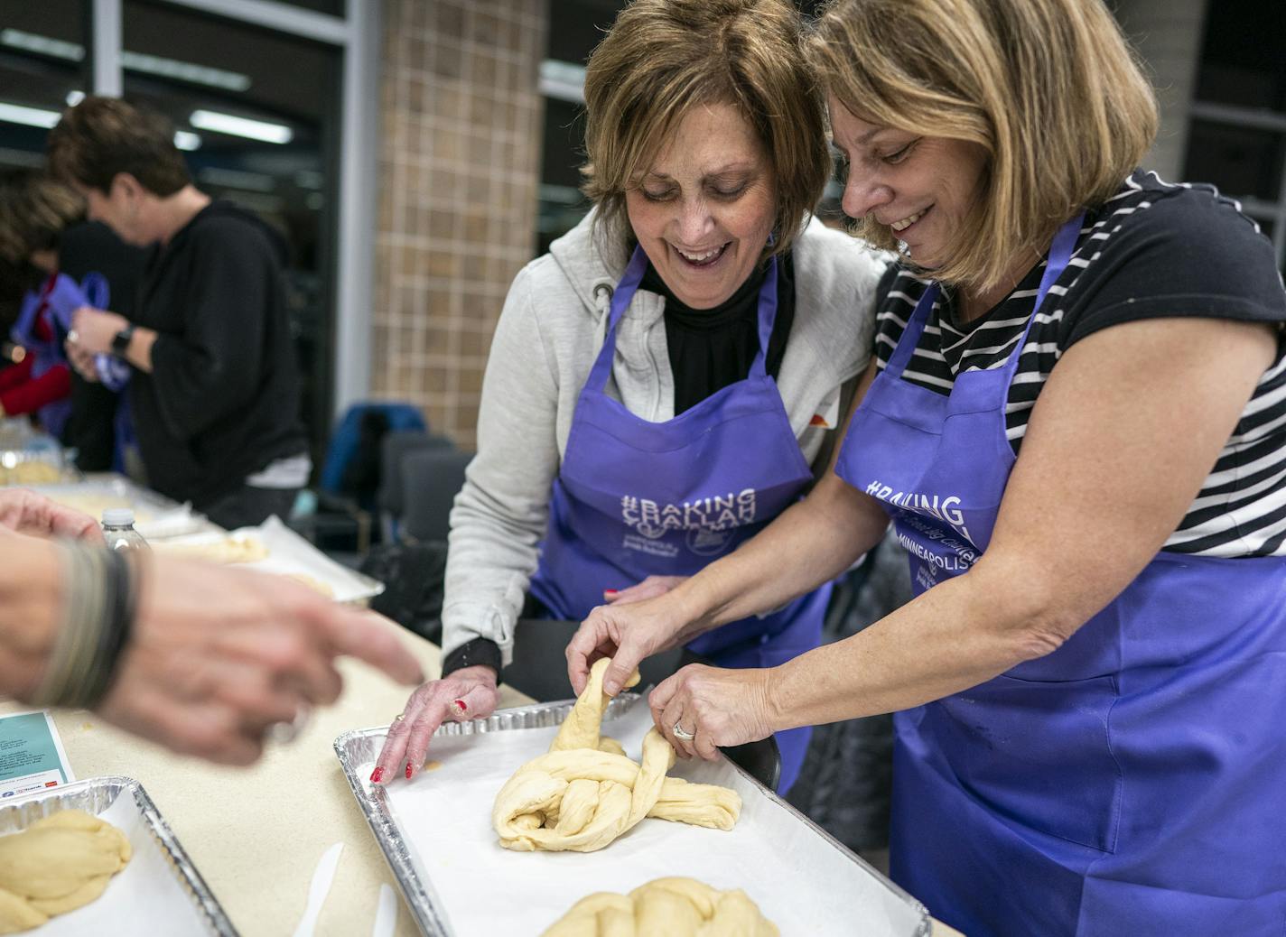 Joanie Rischall, from right, of Plymouth helped first time challah maker Nancy Lehrman, of Plymouth braid her dough during the Great Big Challah Bake. ] LEILA NAVIDI &#x2022; leila.navidi@startribune.com BACKGROUND INFORMATION: More than 500 women and girls participates in the Great Big Challah Bake at Hopkins High School in Minnetonka on Thursday, November 14, 2019.