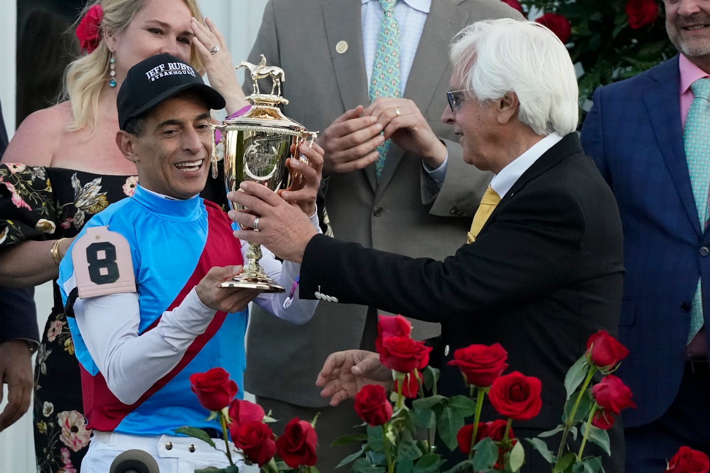 Trainer Bob Baffert hands the winner's trophy to jockey John Velazquez after their victory with Medina Spirit in the 147th running of the Kentucky Derby at Churchill Downs, Saturday, May 1, 2021, in Louisville, Ky. (AP Photo/Jeff Roberson)