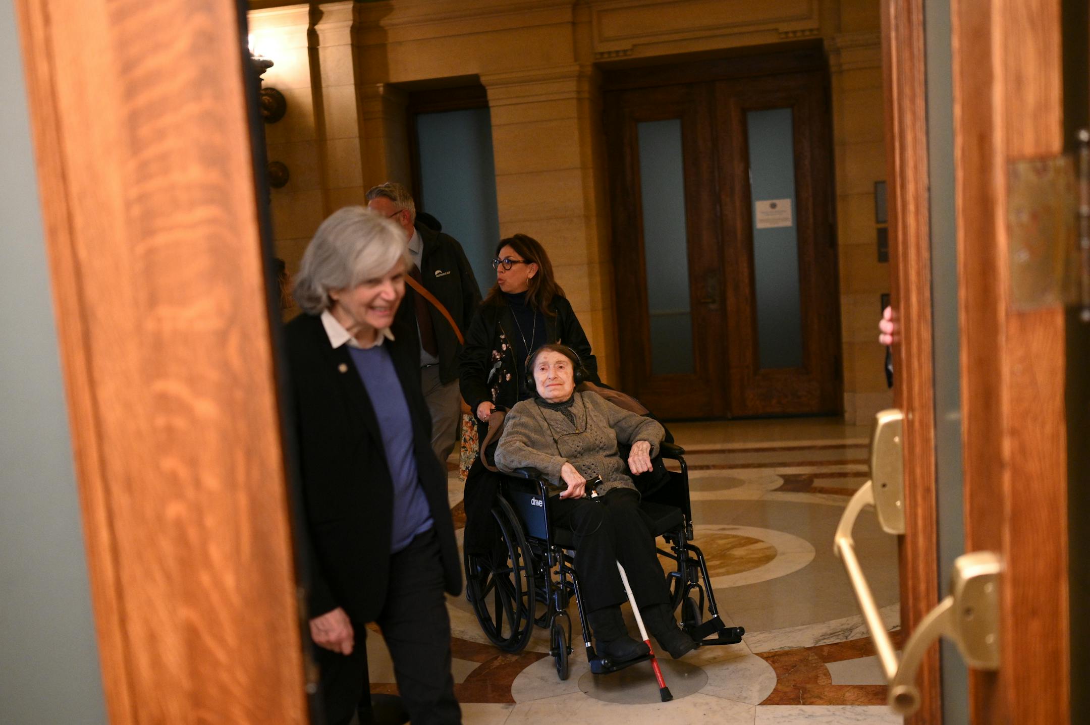Laura Zelle, a child of a holocaust survivor and director of Holocaust education for the Jewish Community Relations Council, pushes the wheelchair of Dora Zaidenweber before they both testified to the education finance committee.
