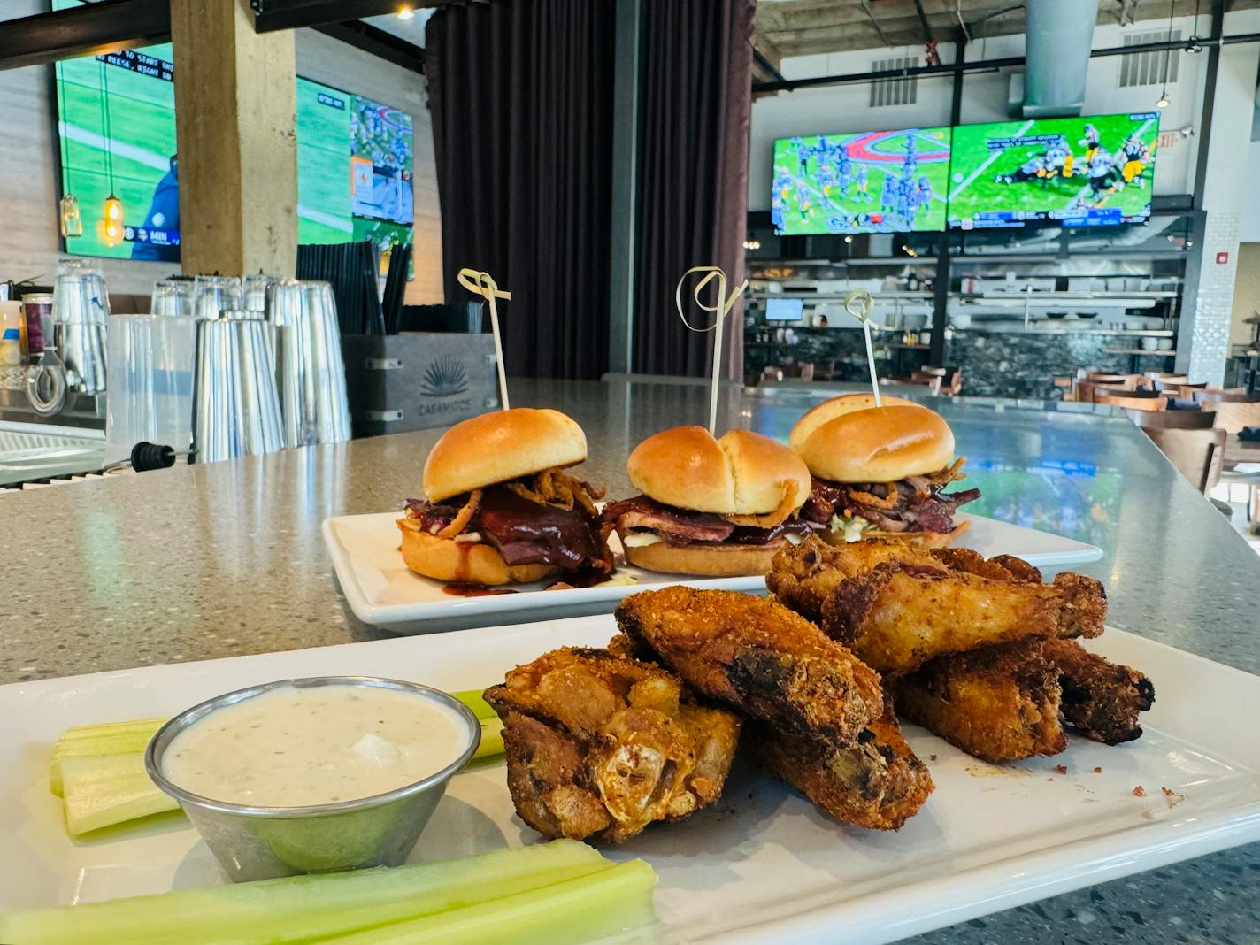 Smoked beef brisket sliders and wings as a Vikings game plays in the backdrop at Parlay Kitchen and Bar in downtown Minneapolis.