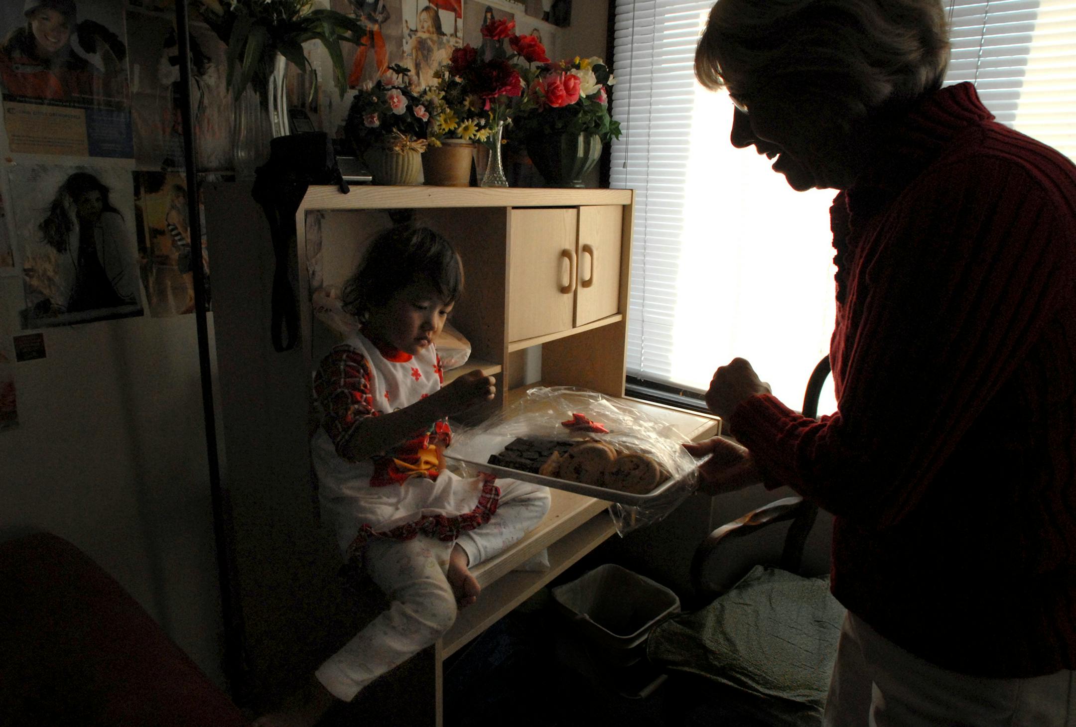 Five-year-old Look Ler Paw studied a cookie from a tray of holiday goodies brought by Thelma James. James sponsors Look's family through a mentor-matching program the school district set up with her church, Arlington Hills United Methodist in Maplewood. "We teach them anything you can possibly imagine if you just arrived here — how to sort their mail, that's the city bus, this is the police," James said.