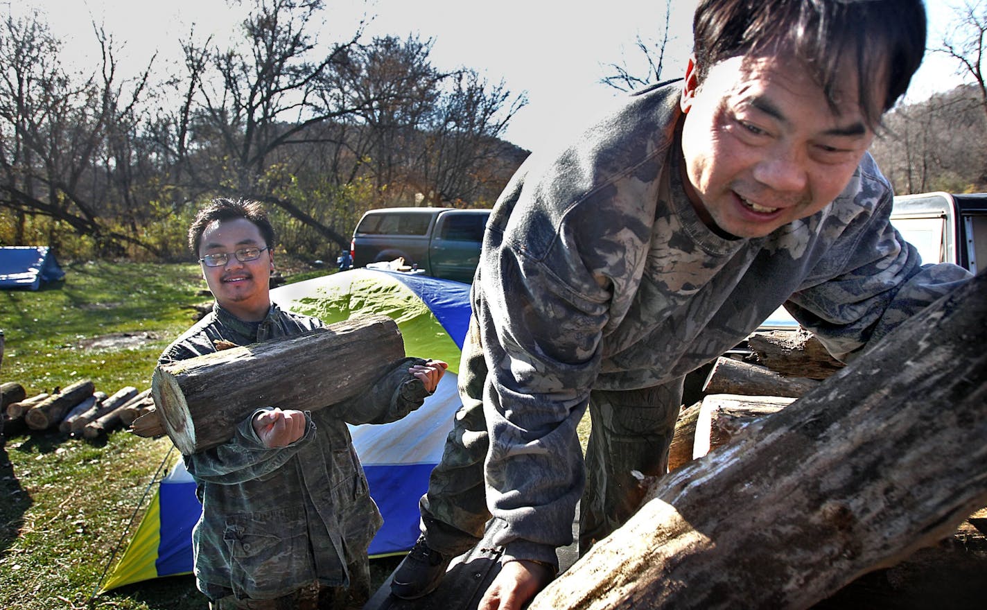 Kong Lor, 21 (left), St. Paul, unloaded firewood with the help of his father, Wa Lor, 41, as the family prepared for Saturday's firearms deer opener.