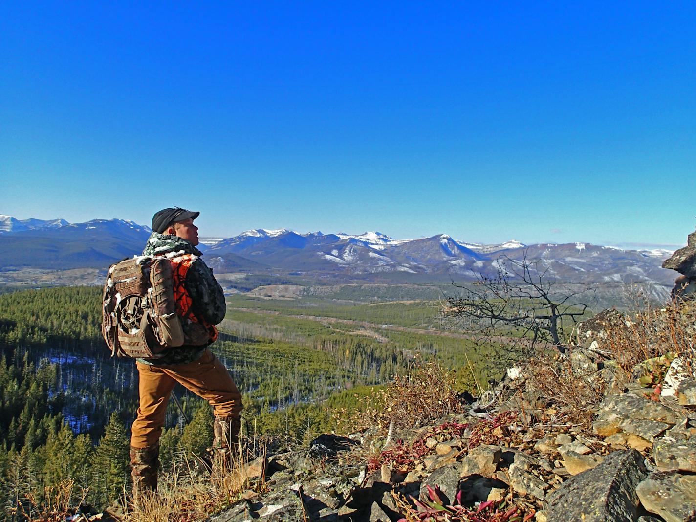 Josh Carlbom, owner with his wife, Niki, of Sun Canyon Lodge and Outfitters, on the edge of Montana's Bob Marshall Wilderness, climbed high on a rocky outcropping while elk hunting to peer through his binoculars, looking for animals. No mechanized travel is allowed in the wilderness, and hunters either hike or travel by horseback. In the far distance is the "Chinese Wall,'' a unique geological formation that rises in the wilderness about 1,000 feet for 15 miles along the continental divide.