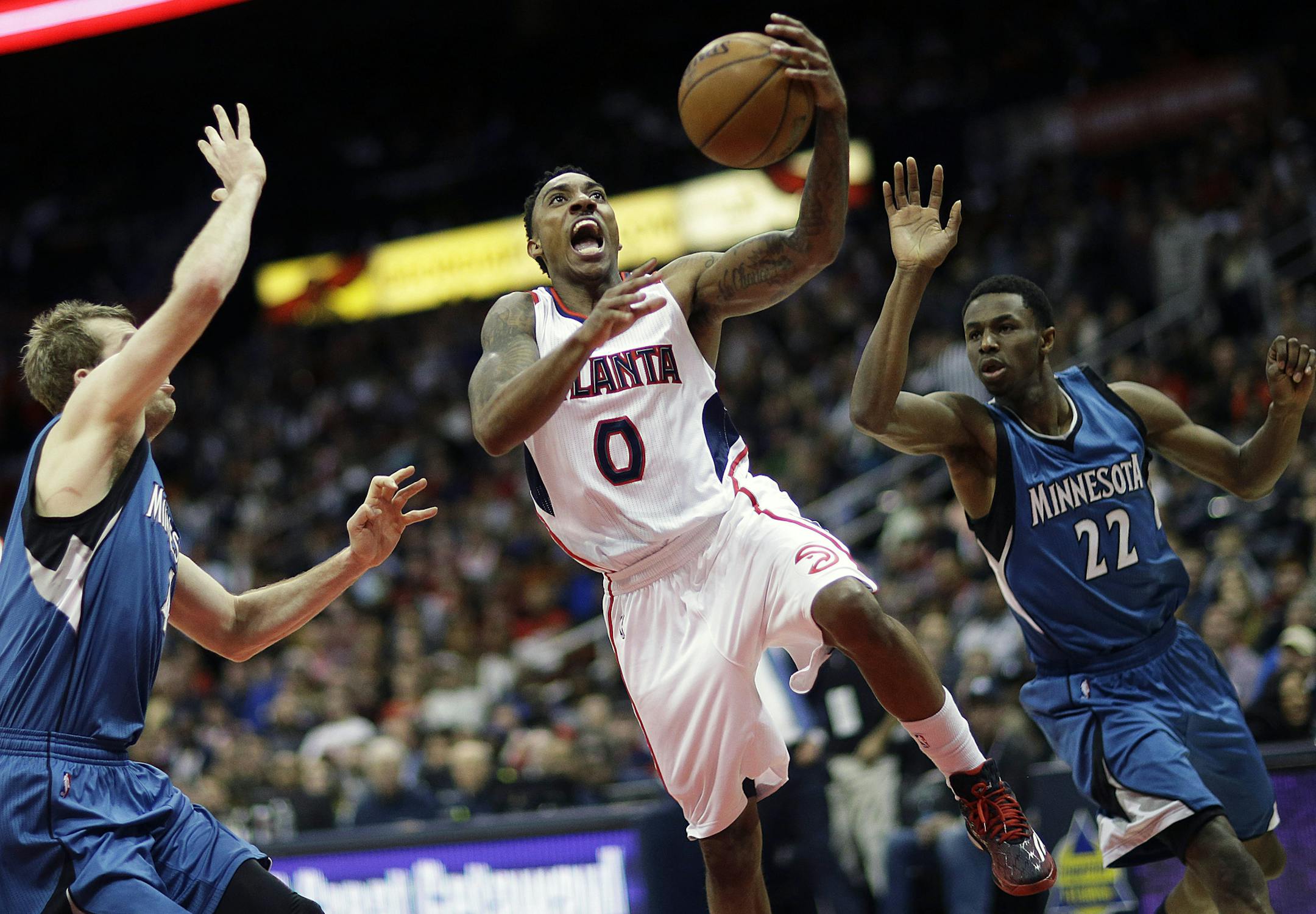 Atlanta Hawks' Jeff Teague, center, shoot against the defense of Minnesota Timberwolves' Robbie Hummel, left, and Andrew Wiggins, right, in the second quarter of an NBA basketball game, Sunday, Jan. 25, 2015, in Atlanta. (AP Photo/David Goldman)