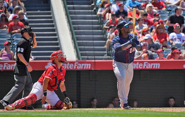 Minnesota Twins' Miguel Sano, right, hits a two-run home run as Los Angeles Angels catcher Juan Graterol, center, watches along with home plate umpire