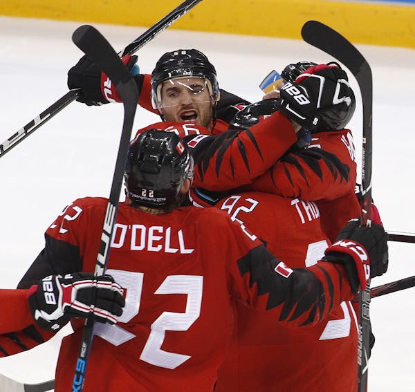 Maxim Noreau (56), of Canada, celebrates with his teammates after scoring a goal against Finland during the third period of the quarterfinal round of 