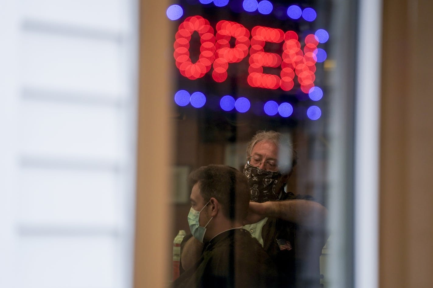 Owner Paul Furrer cuts the hair of Jeff Jones at Rick's Barber Shop Thursday, May 14, 2020, in Waukesha, Wis. The store re-opened after the Wisconsin Supreme Court struck down Gov. Ever's stay-at-home order on Wednesday. (AP Photo/Morry Gash)