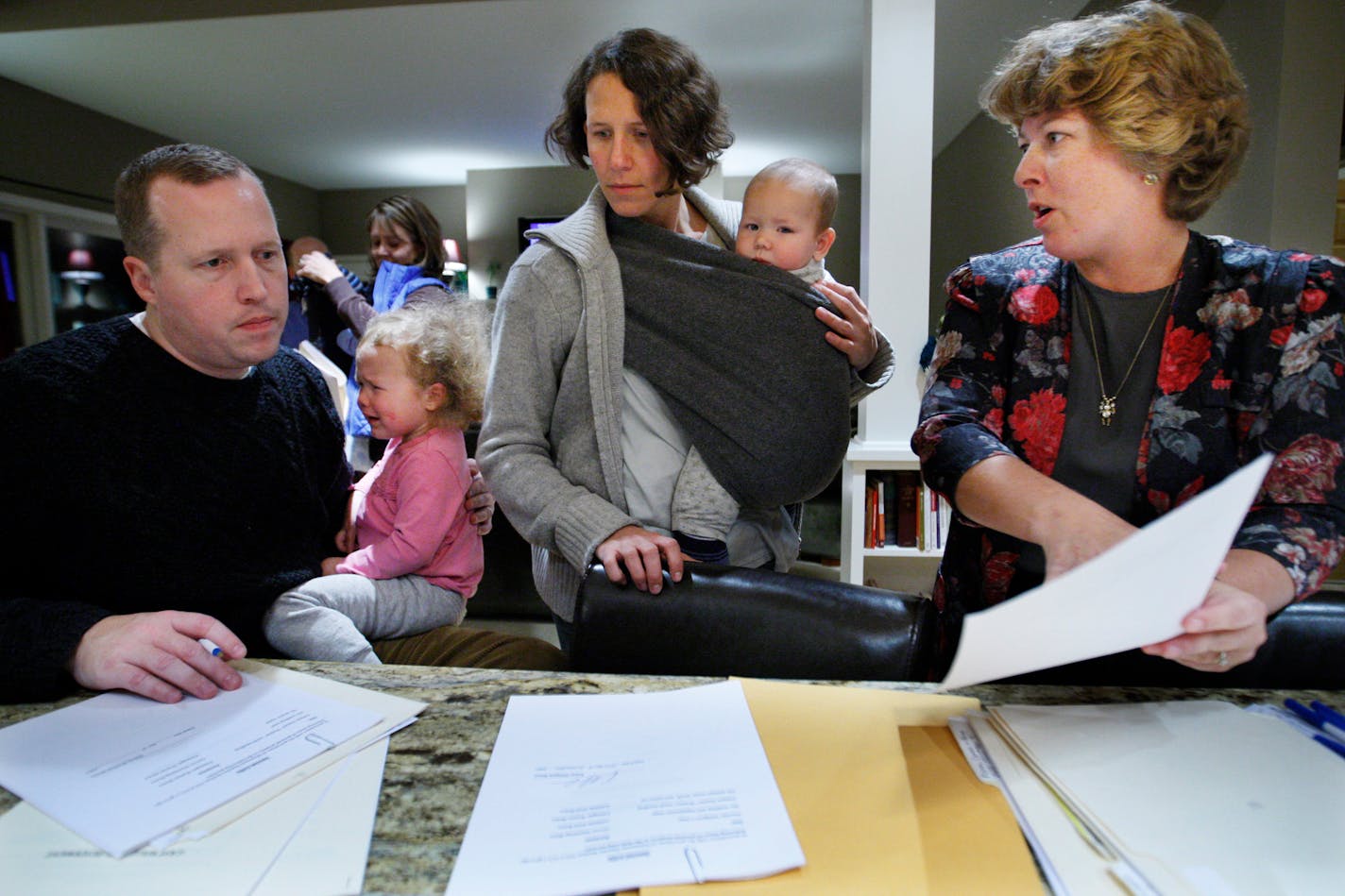 Richard Tsong-Taatarii/rtsong-taatarii@startribune.com Woodbury, MN;11/15/07;left to right:At a will signing party, Staven Bruce(cq) holds daughter Adelaide. Wife Karen holds infant, Finnegan, seven months. Lawyer Marjorie J. Holsten goes through the paperwork getting the couples to sign and witness the wills for each other while she notarizes them.