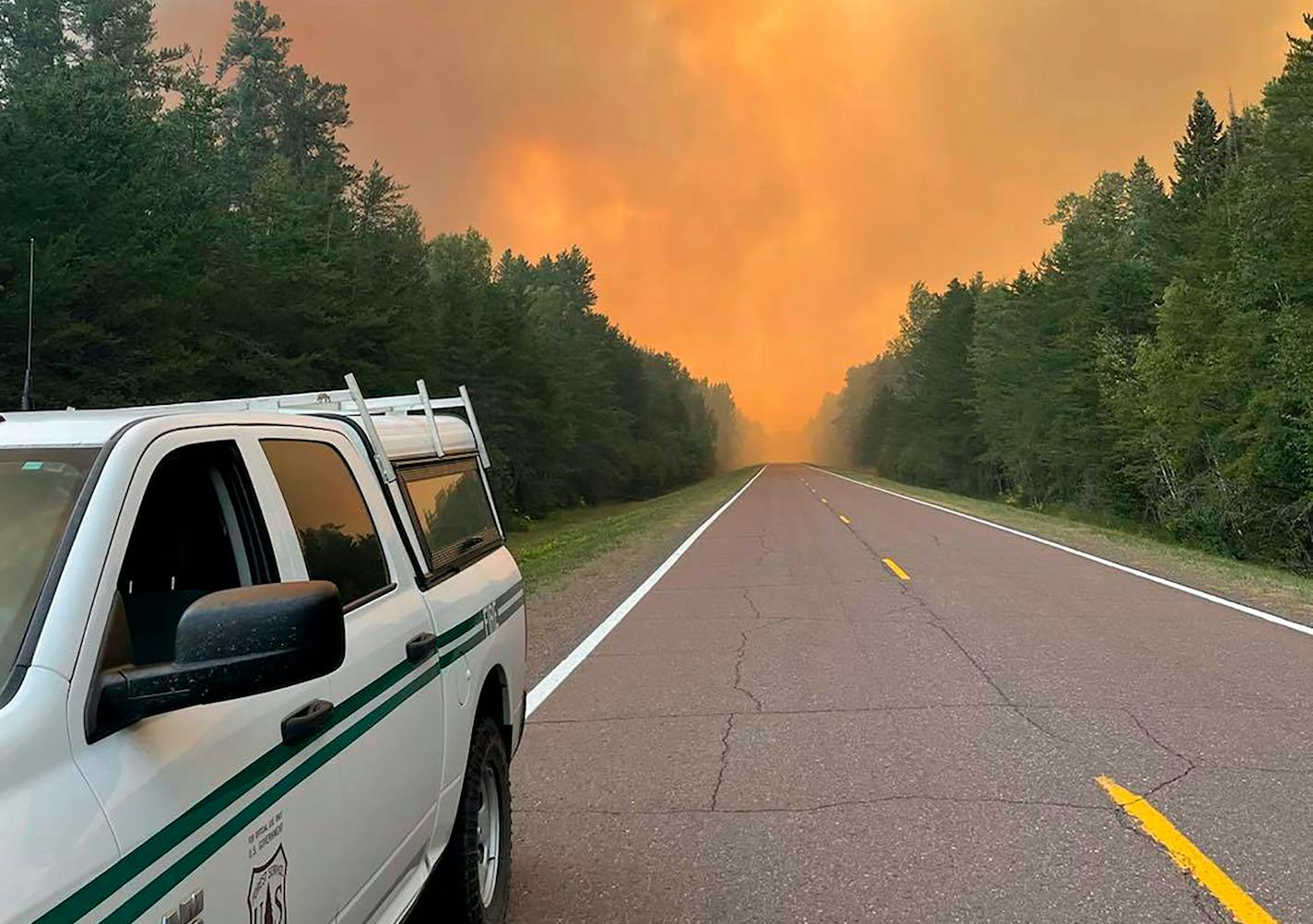 This Thursday, Aug. 19, 2021, photo provided by the U.S. Forest Service, a rapidly growing wildfire rises in the background in northeastern Minnesota. U.S. Forest Service officials have warned home and cabin owners who fled a wildfire in northeastern Minnesota that the winds could shift this weekend, putting their properties in danger. Dozens of people got the warning at a public meeting Thursday, Aug. 19, 2021, evening in the small town of Finland, where officials gave them the latest about the Greenwood Lake fire and their strategy for trying to stop it. (Nick Petrack/U.S. Forest Service via AP)