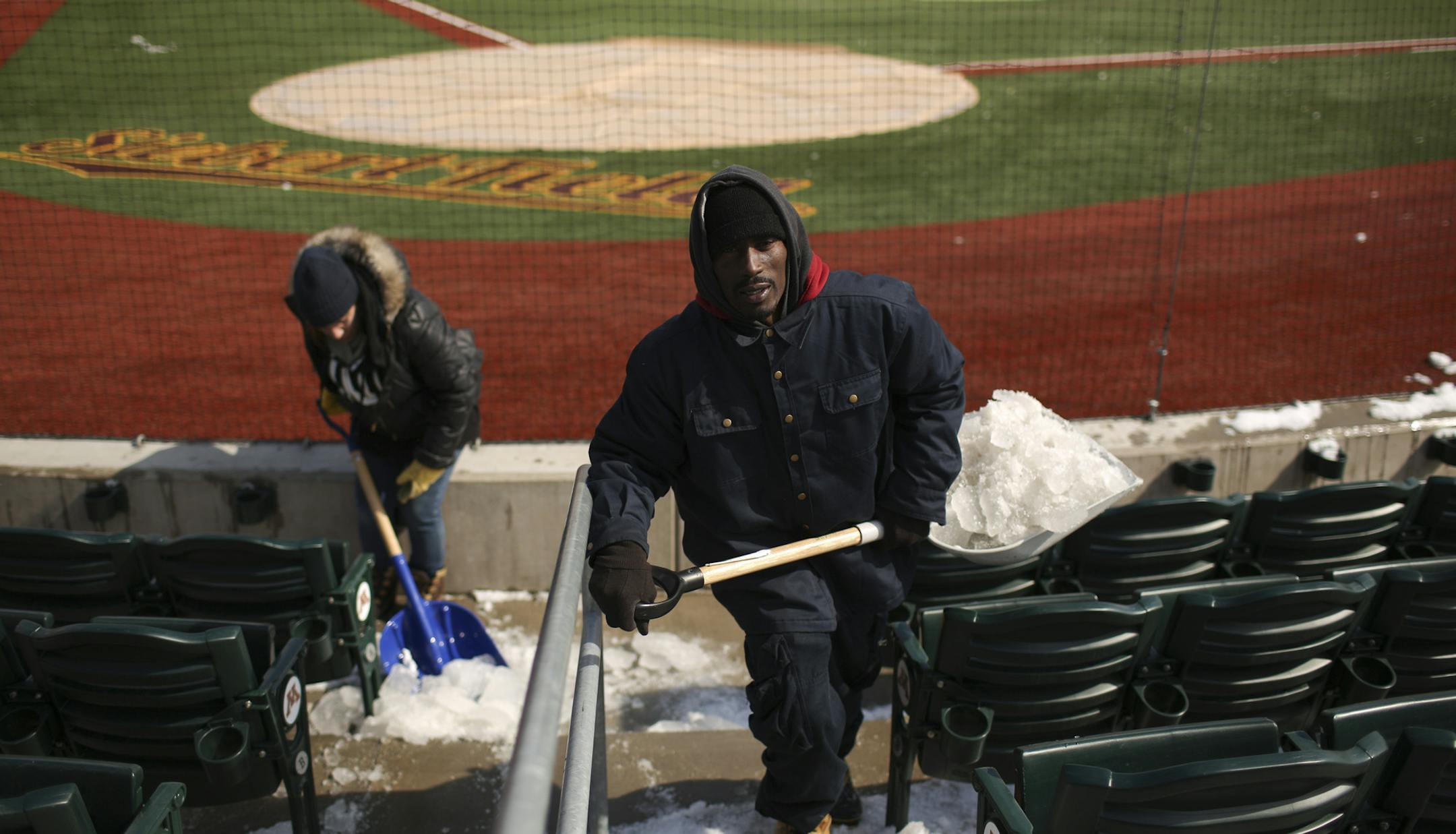 Carlos Clark, foreground, and Angelique Simons were among a crew removing snow at Siebert Field on Monday. The Gophers are scheduled to play host to Michigan State this weekend.