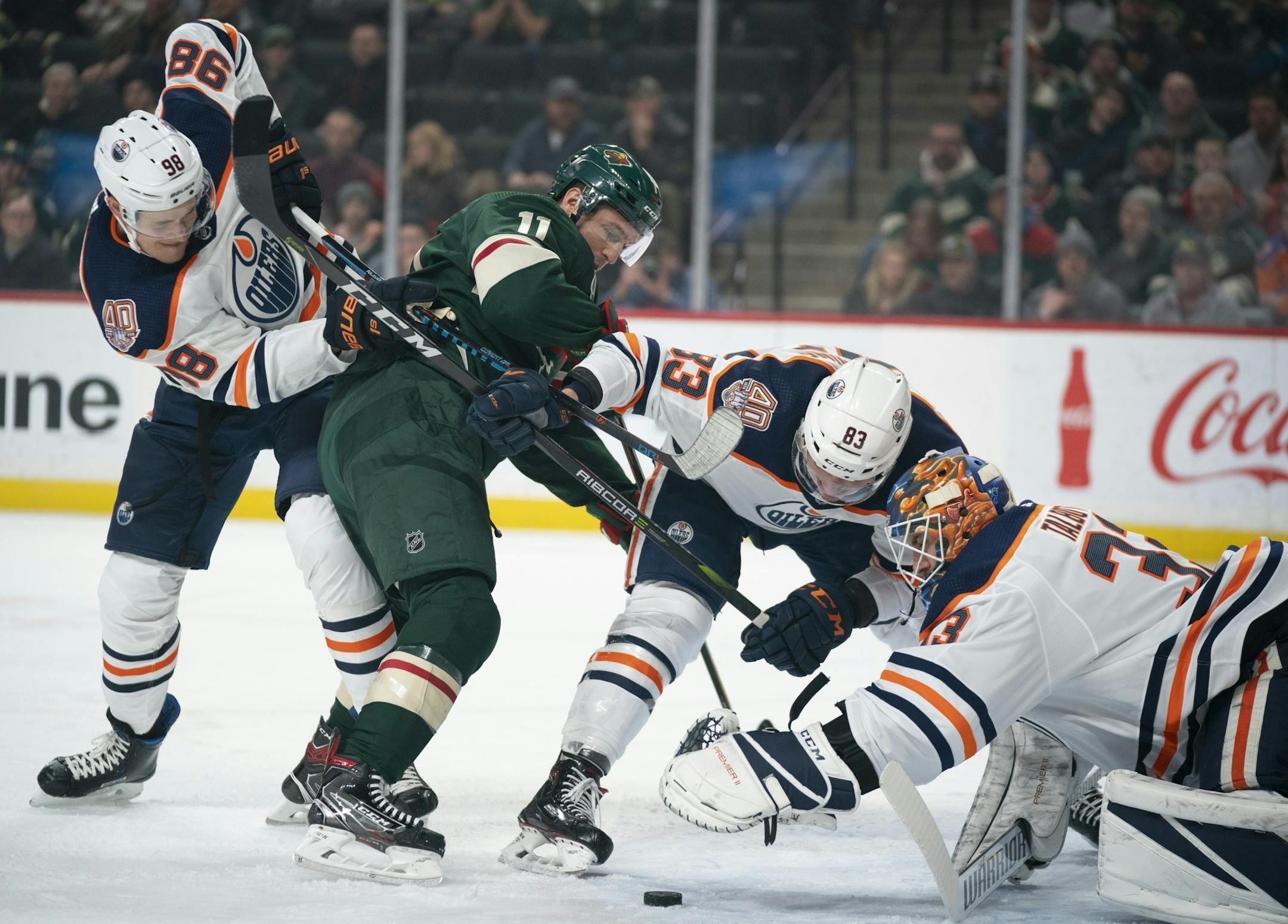 Edmonton Oilers goaltender Cam Talbot (33) reached for the puck in front of him in the first period while the Oilers defenseman Matt Benning (83) and right wing Jesse Puljujarvi (98) held off Minnesota Wild left wing Zach Parise (11).