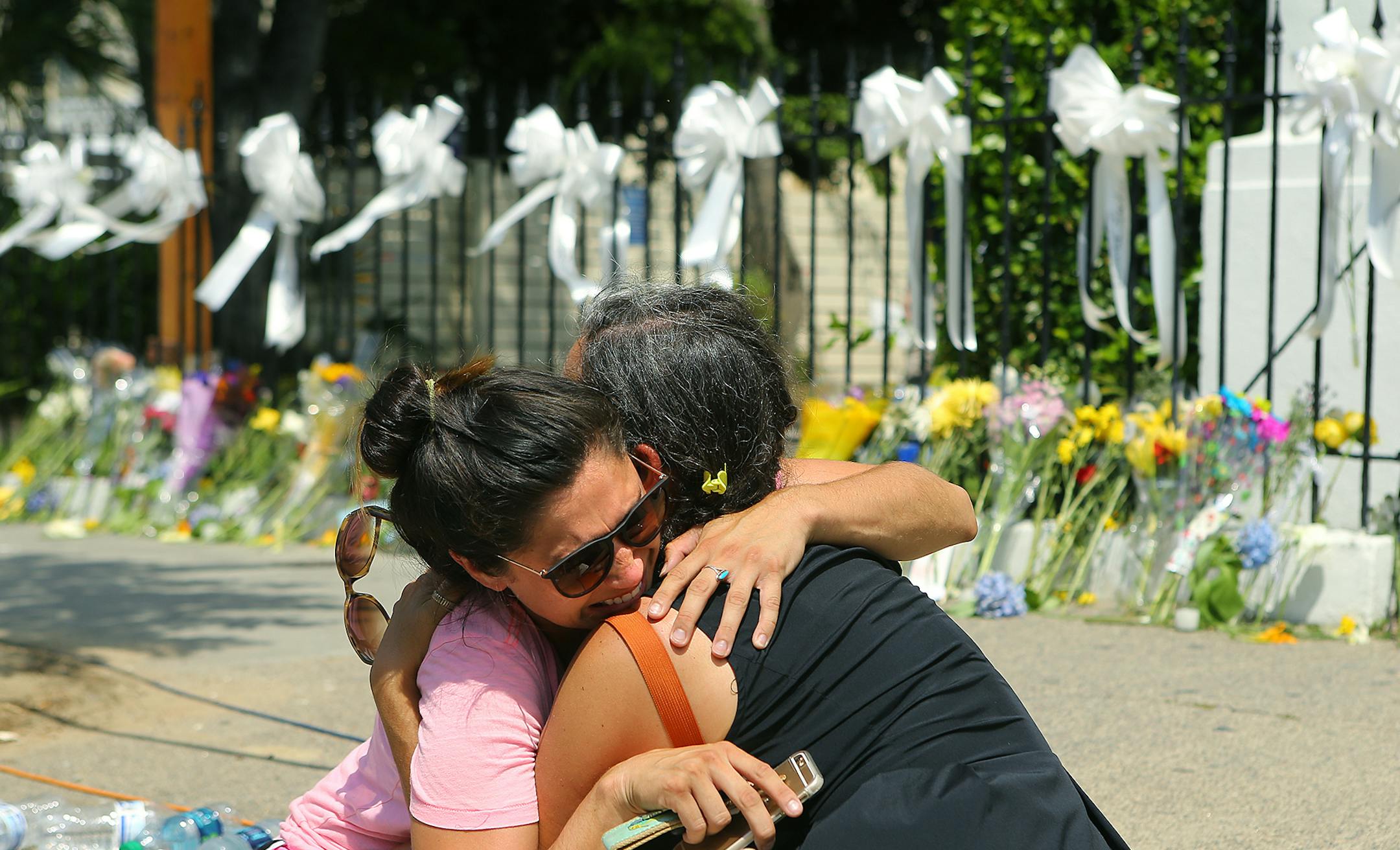 Stewart Watson, right, of Baltimore, comforts Maranda Mincey ofCharleston, as they both become emotional while visiting the sidewalk memorial at the Emanuel African Methodist Episcopal Church on Friday, June 19, 2015, in Charleston, S.C. The people of Charleston built a memorial and planned a vigil Friday to repudiate whatever a gunman would hope to accomplish by killing nine black community leaders inside one of the nation's most important African-American churches. (Curtis Compton/Atlanta Jour