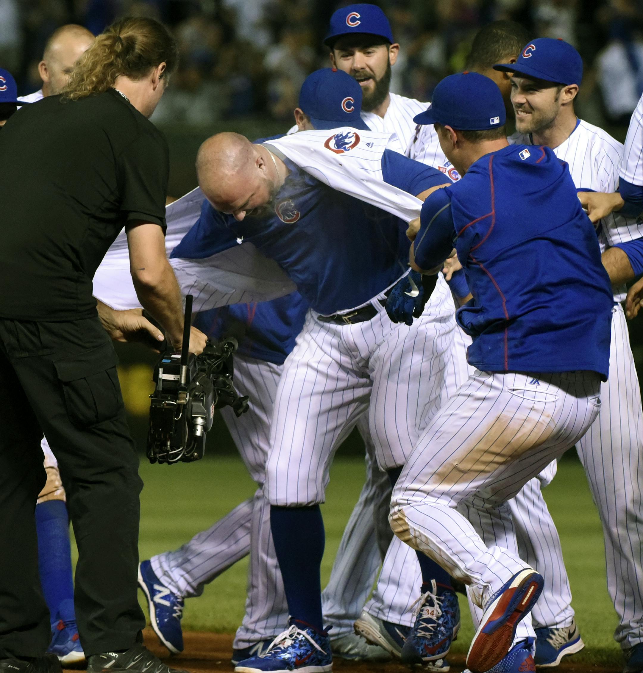 Chicago Cubs players rip the jersey off of Jon Lester, center, after he hit a game winning sacrifice bunt which scored Jason Heyward in the twelfth inning of a baseball game against the Seattle Mariners on Sunday, July 31, 2016, in Chicago. The Chicago Cubs beat the Seattle Mariners 7-6. (AP Photo/Matt Marton)
