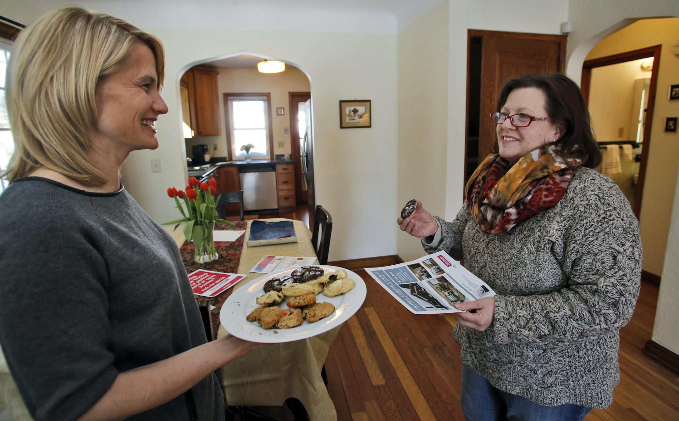Marcy Wengler is a real estate agent in St. Paul who has found difficulty selling houses this winter due to the harsh weather conditions. She has responded by making cookies and coffee for those that endure the snow and cold to tour her sale homes. Wengler, left, offered a plate of cookies to Tracy Oxford of St. Paul as she toured a home in St. Paul. (MARLIN LEVISON/STARTRIBUNE(mlevison@startribune.com)
