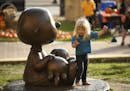 Mira Decelle-Burback, 2, looked at bronze statue of Charlie Brown and his dog Snoopy, while at the event with her dad, Dale Burback, Tuesday evening i