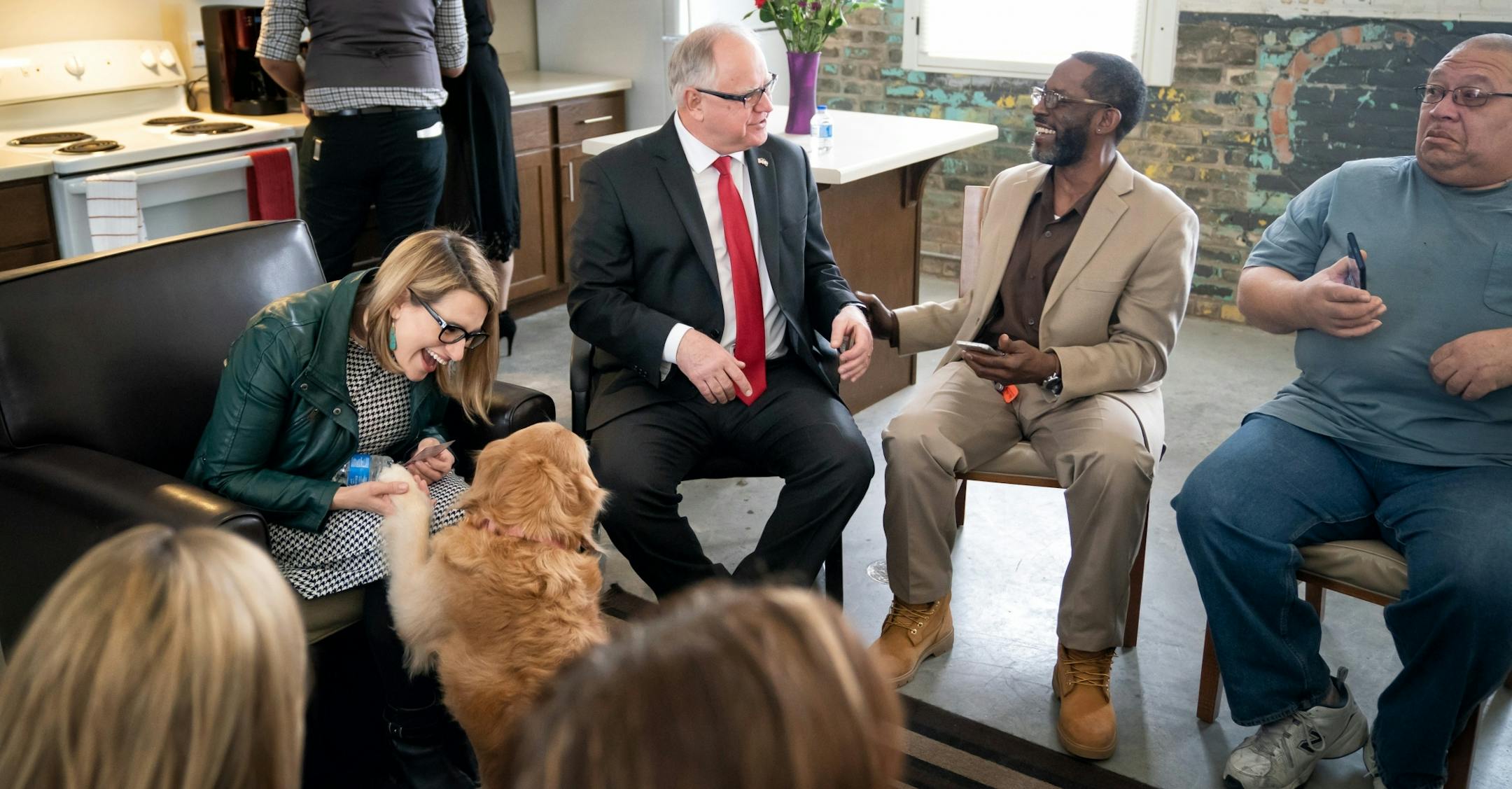 Lieutenant Governor Flanagan and Governor Tim Walz couldn't resist petting Dutches a therapy dog at the Upper Post Veterans Community at Fort Snelling, remodeled as a place to live for formerly homeless veterans. He touted it as an example of important and appropriate investments in Minnesota as he released his $1.3 billion bonding proposal. On the right are veterans Ronnie Wadell and George Trawick. Dutchess is owned by Austin Poons, one of the first to move into the facility.