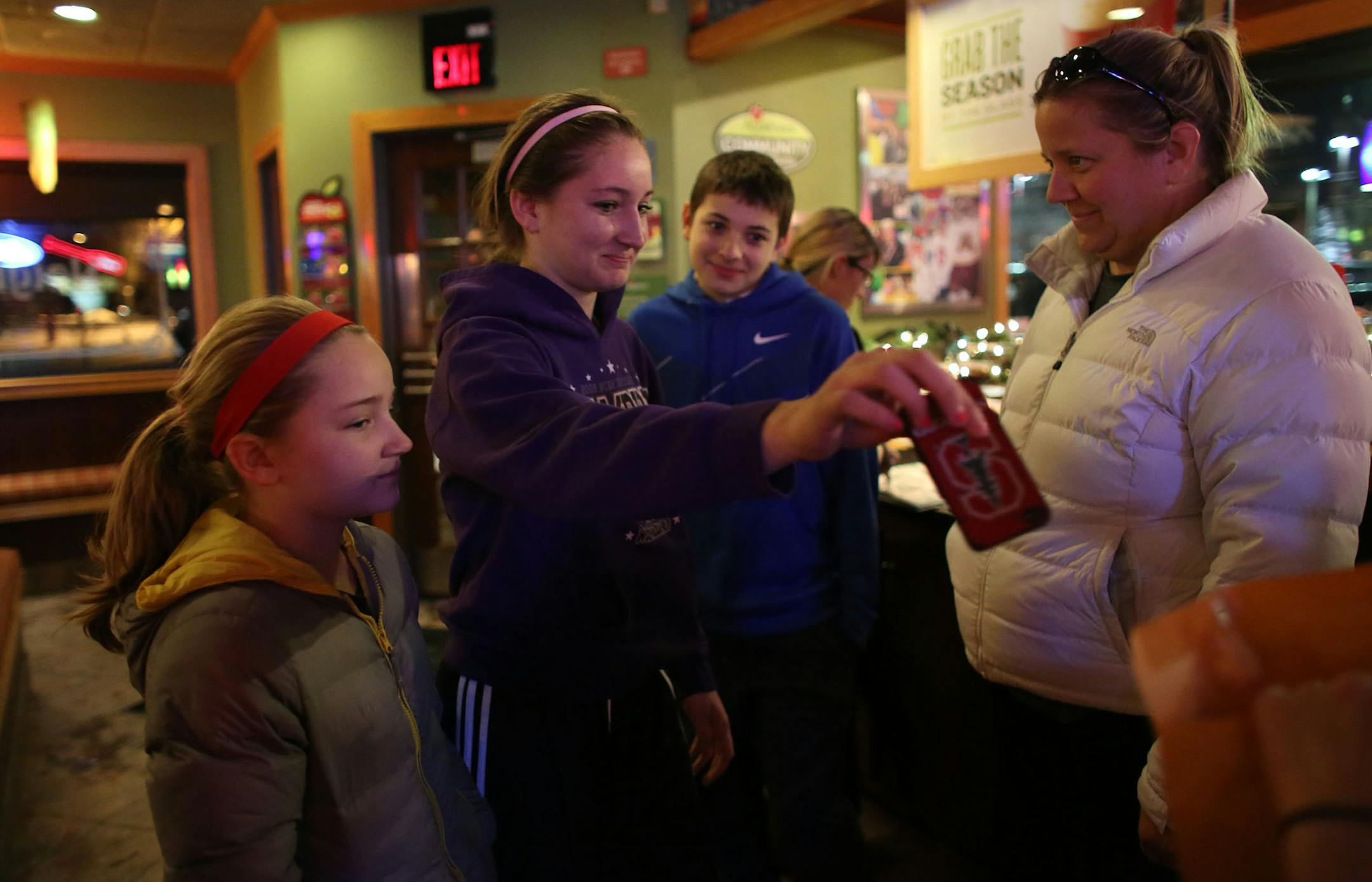 With her siblings Nicole, 10, and Ryan, 13, and mother Julie waiting Brooke Bowlin, 15, finally gave up her phone for the duration of their dinner at the Applebee's in Chanhassen Wednesday, December 11, 2013. Chanhassen High School students were asking patrons to not use their phones during their dinner as a part of a project for school. ] (KYNDELL HARKNESS/STAR TRIBUNE) kyndell.harkness@startribune.com