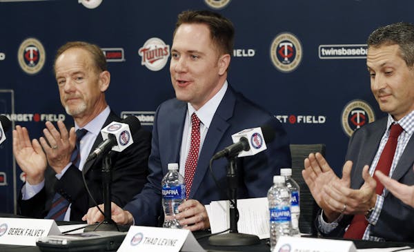 Minnesota Twins owner, Jim Pohlad, left, and new general manager Tad Levine, right, applaud the introduction of new chief baseball officer Derek Falve