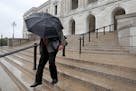 A man shielded himself from the rain with an umbrella as he walked down the steps of the State Capitol Saturday in St. Paul.