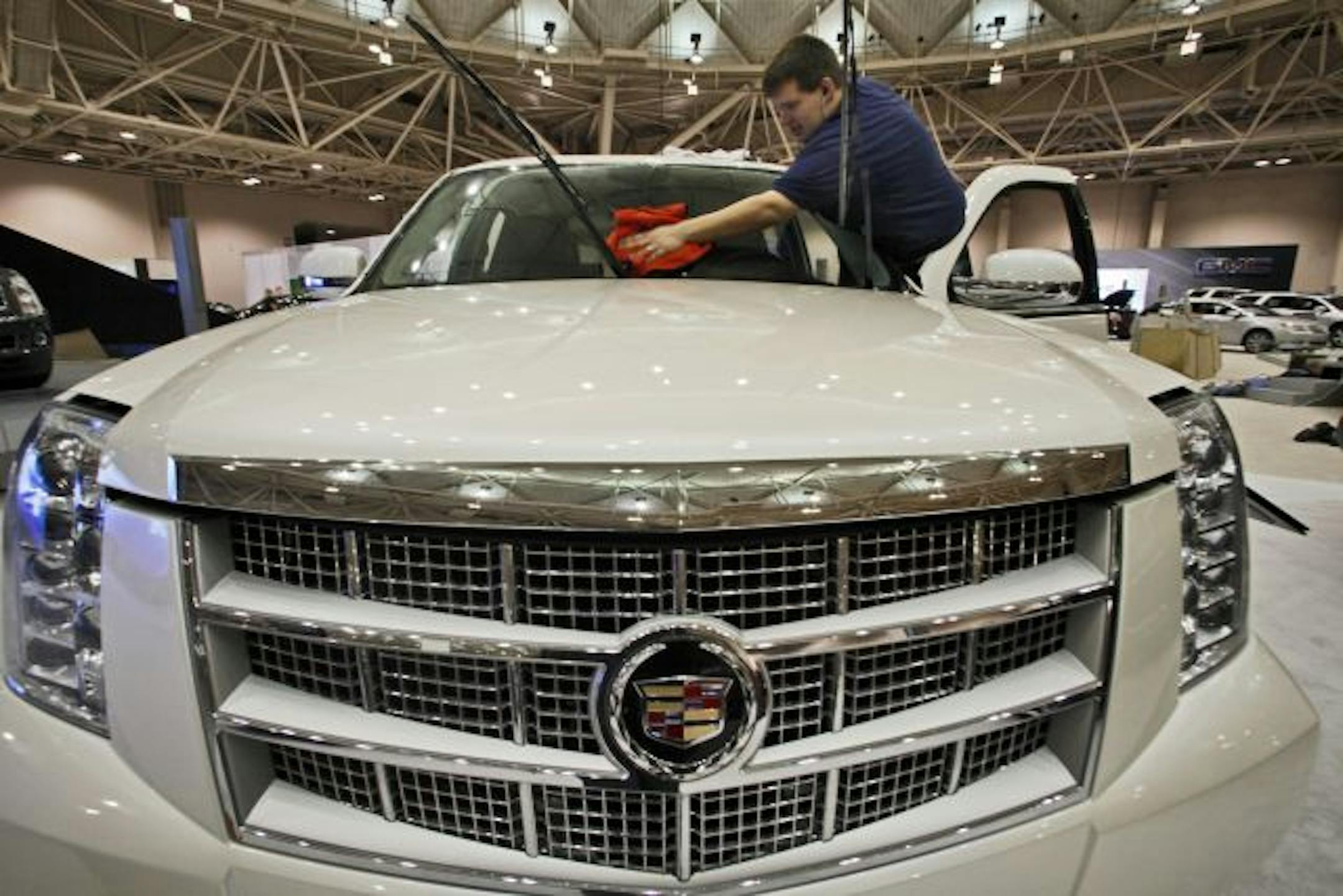 Professional detailer Matthew Cox puts the final cleaning touches on a new Cadillac Escalade on display on the convention center floor.