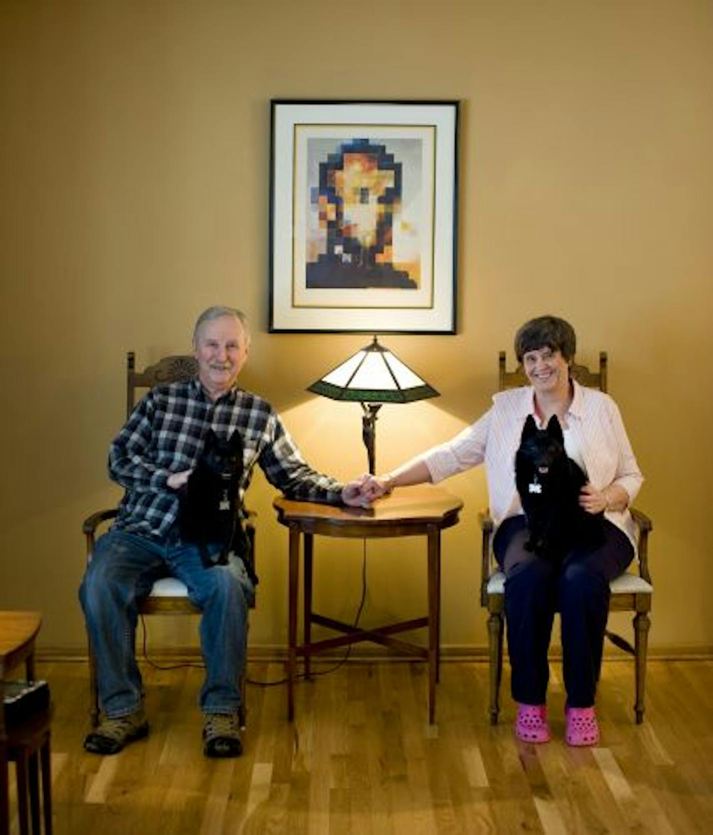 Jim and LaVonne Rasmusson with their two Schipperke dogs Maya and Shadow. Behind them is their favorite piece of art, a Salvador Dali print Gala Nude/Abraham Lincoln.