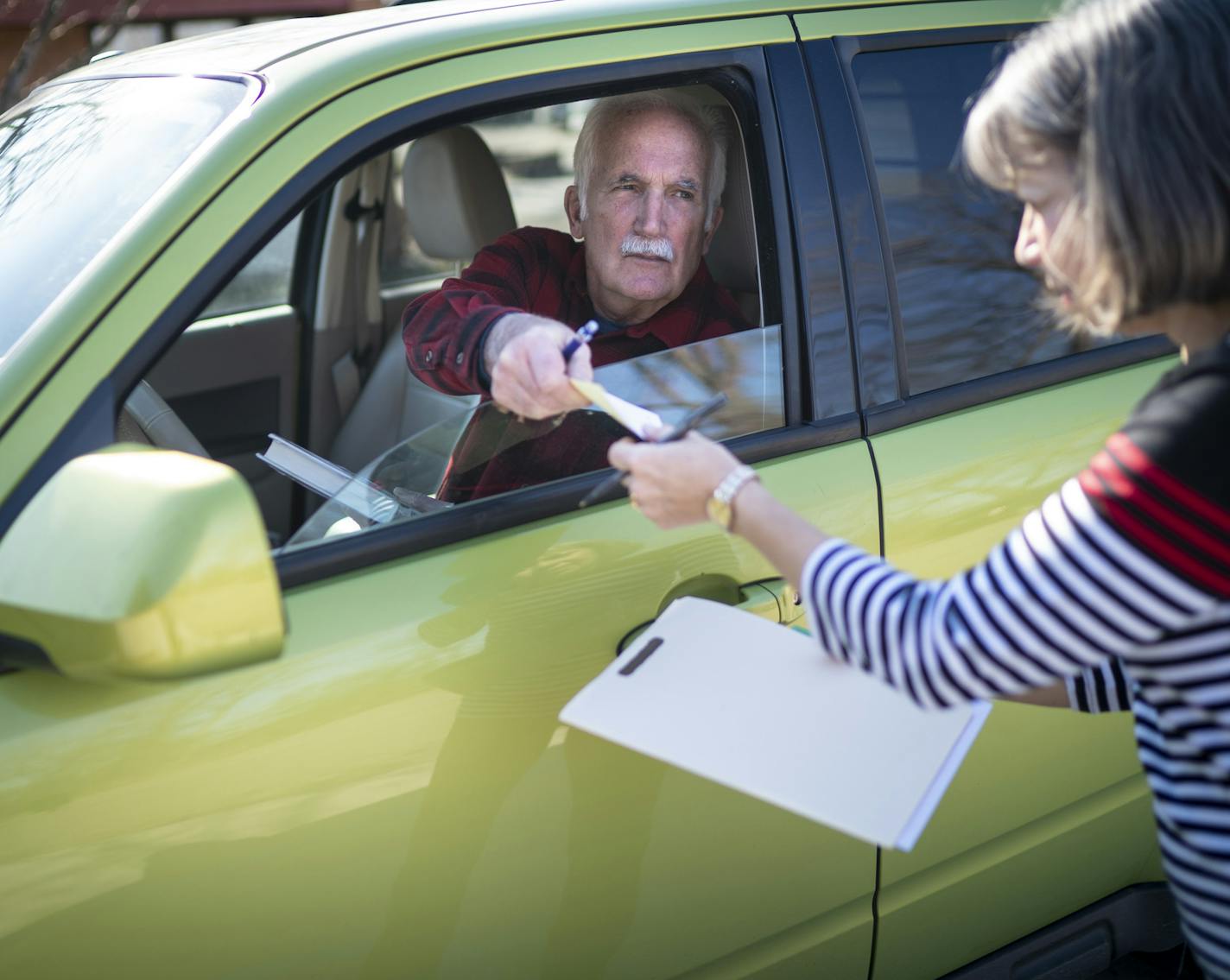 Dr. John Goeppinger, 71, handed RN Verna Fricke a prescription he wrote from his car as she dealt with a patient over the phone at the C.A.R.E. Clinic in Red Wing, Minn., on Tuesday, March 31, 2020. Goeppinger is a retired family medicine doctor who is volunteering for the clinic but keeping his distance by staying in his car and consulting with nurses due to the Covid-19 epidemic. ] RENEE JONES SCHNEIDER &#xa5; renee.jones@startribune.com