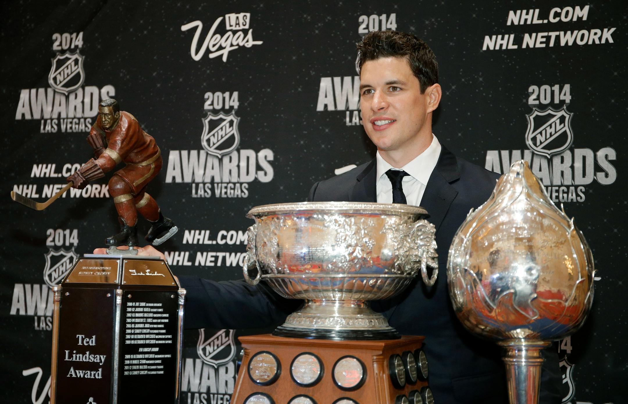 Pittsburgh Penguins' Sidney Crosby posed with the Ted Lindsay Award, the Art Ross Trophy and the Hart Trophy, from left, after winning the awards at the NHL Awards on Tuesday, June 24, 2014, in Las Vegas. (AP Photo/John Locher)