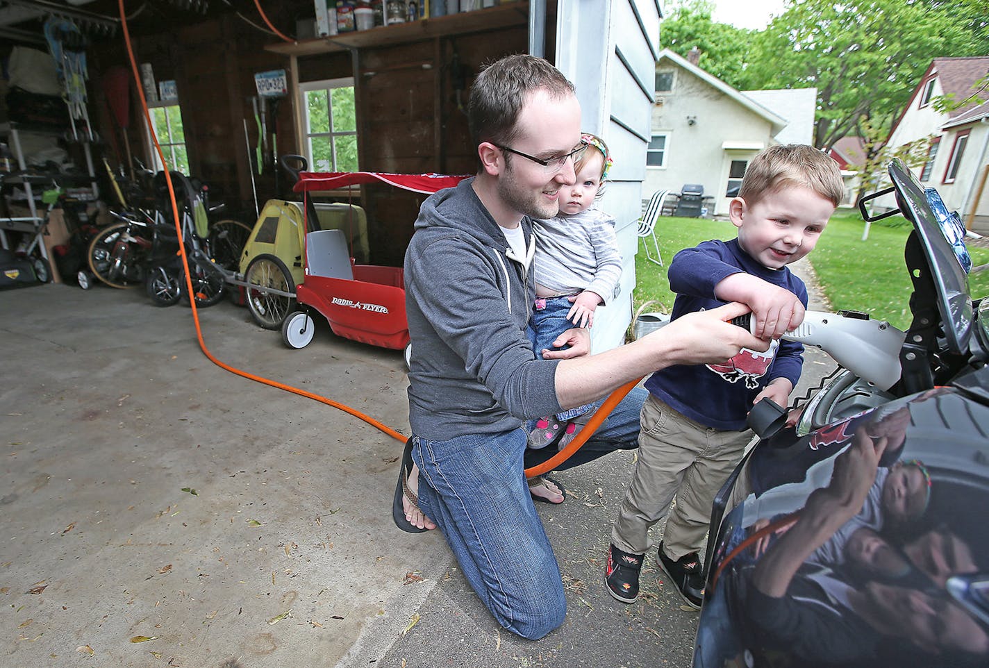 Tyler Sahnow gave his son Ethan, 3, a lesson in plugging in the Nissan Leaf from the EV charging station, Wednesday, May 20, 2015 in Minneapolis, MN. Shallow, who was holding his daughter Cora, 1, uses a Level 2 charger allowing only four hours to charge the car. Major electric utilities in MN begin offering electric vehicle charging rates. ] (ELIZABETH FLORES/STAR TRIBUNE) ELIZABETH FLORES &#x2022; eflores@startribune.com