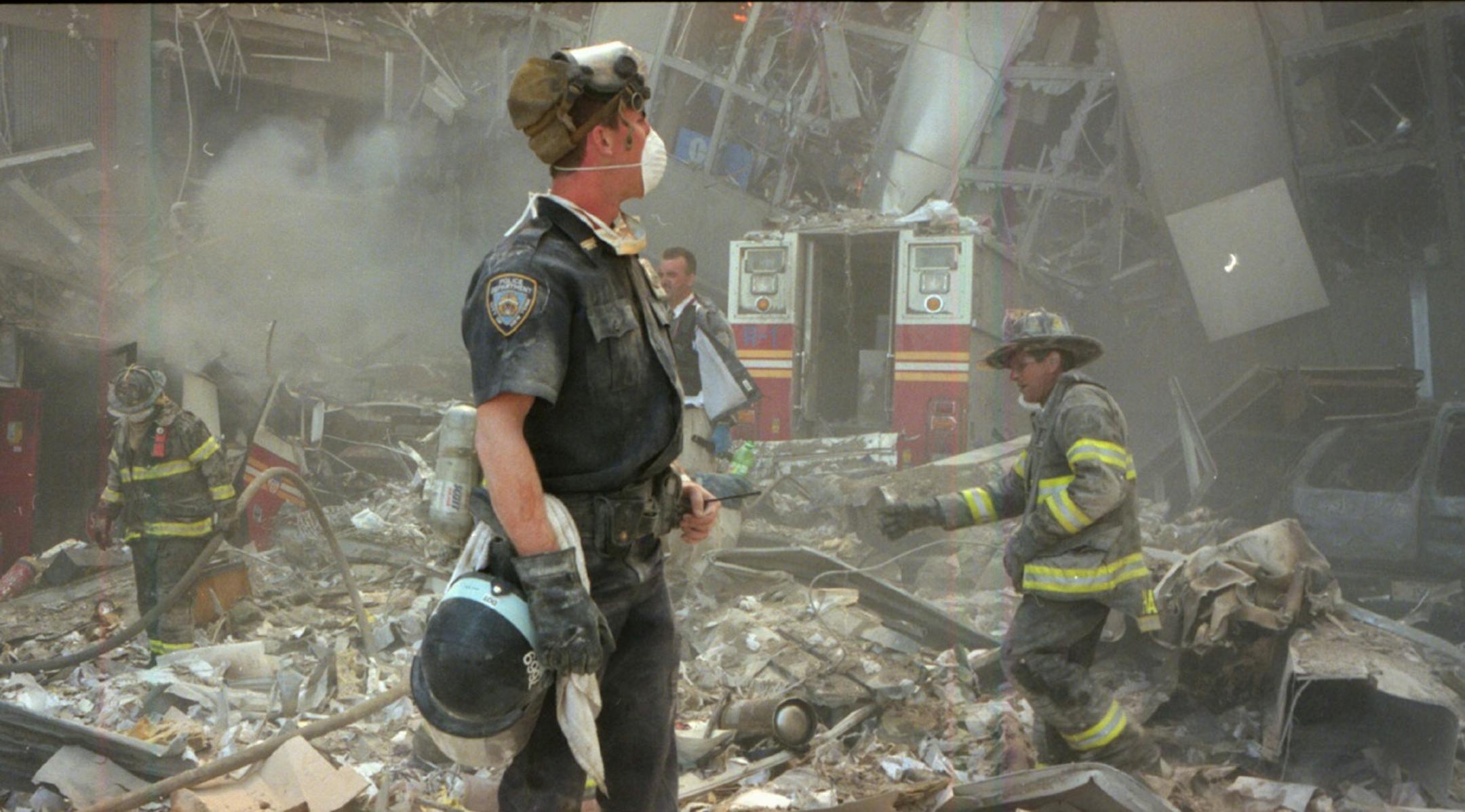 (NYT114) NEW YORK -- Aug. 8, 2002 -- 9-11-ANNIVERSARY-14 --Firefighters and a police officer just after the collapse of the World Trade Center on Sept. 11, 2001. (Angel Franco/The New York Times)