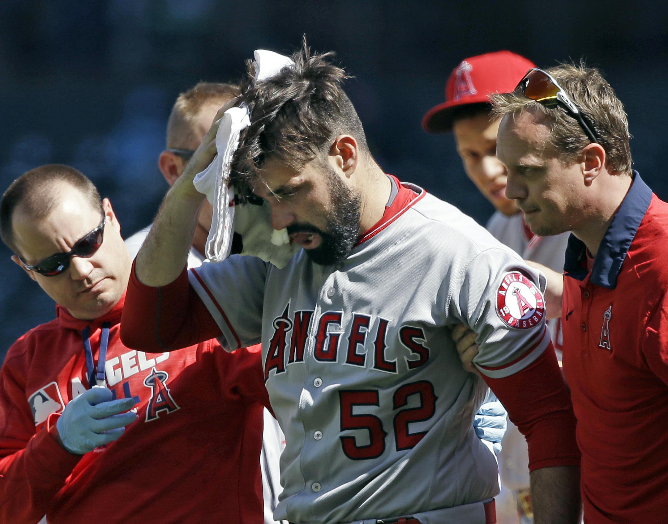 Los Angeles Angels starting pitcher Matt Shoemaker is assisted off the field after being hit by a line drive from Seattle Mariners' Kyle Seager in the second inning of a baseball game, Sunday, Sept. 4, 2016, in Seattle. (AP Photo/Elaine Thompson)