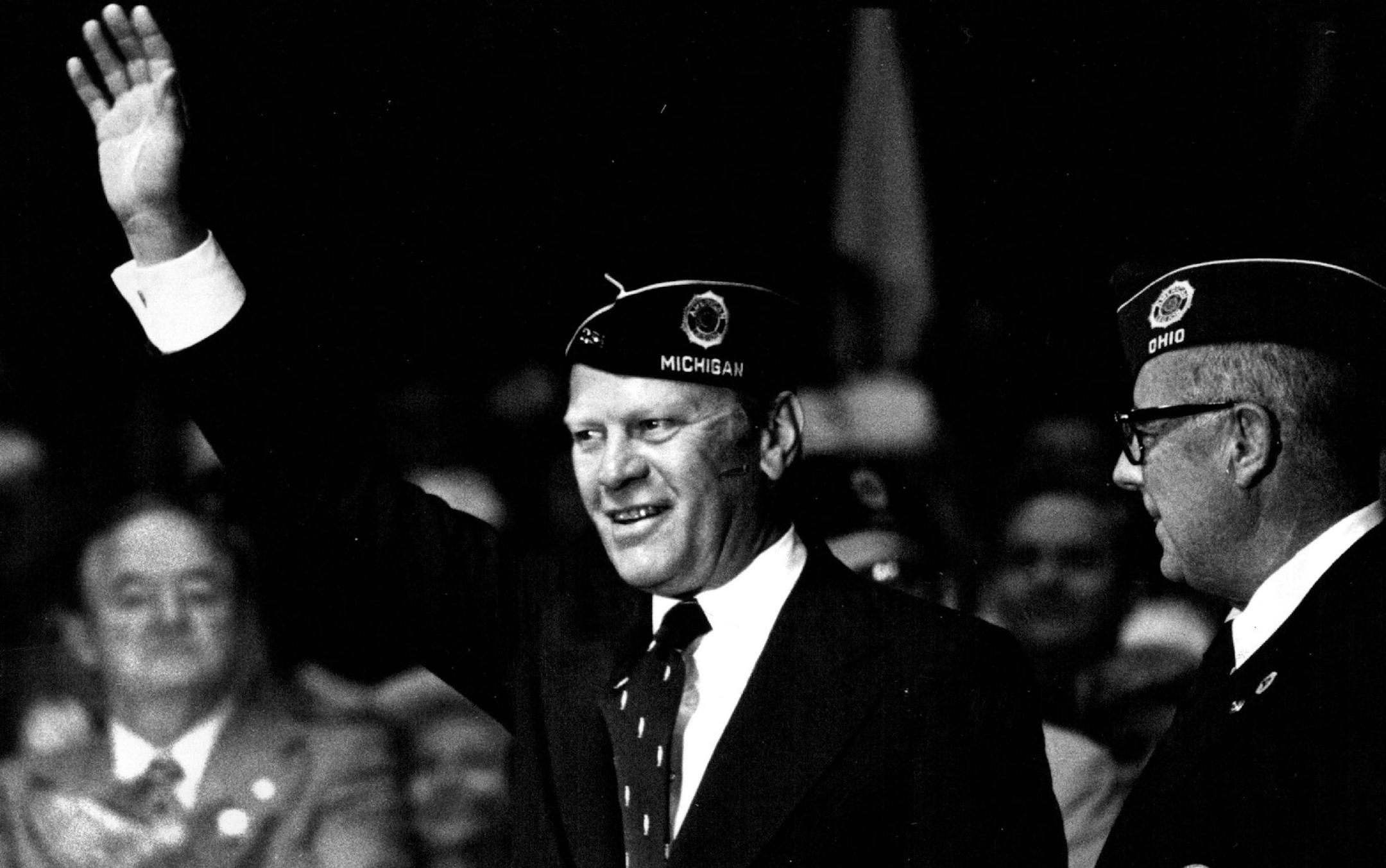 August 20, 1975 Visiting Legionnaires, state Republican leaders and ordinary Minnesotans got a chance to see President Ford the flesh during his visit to Minneapolis Tuesday. Cameras and dark blue overseas caps seemed to be everywhere. At right Legion official watched the president acknowledge applause from 4.out 8,000 members at the Minneapolis Auditorium. Behind Ford at left was Sen. Hubert Humphrey, D-Minn. Below, shutters clicked and hands reached as Ford moved into a crowd that greeted him