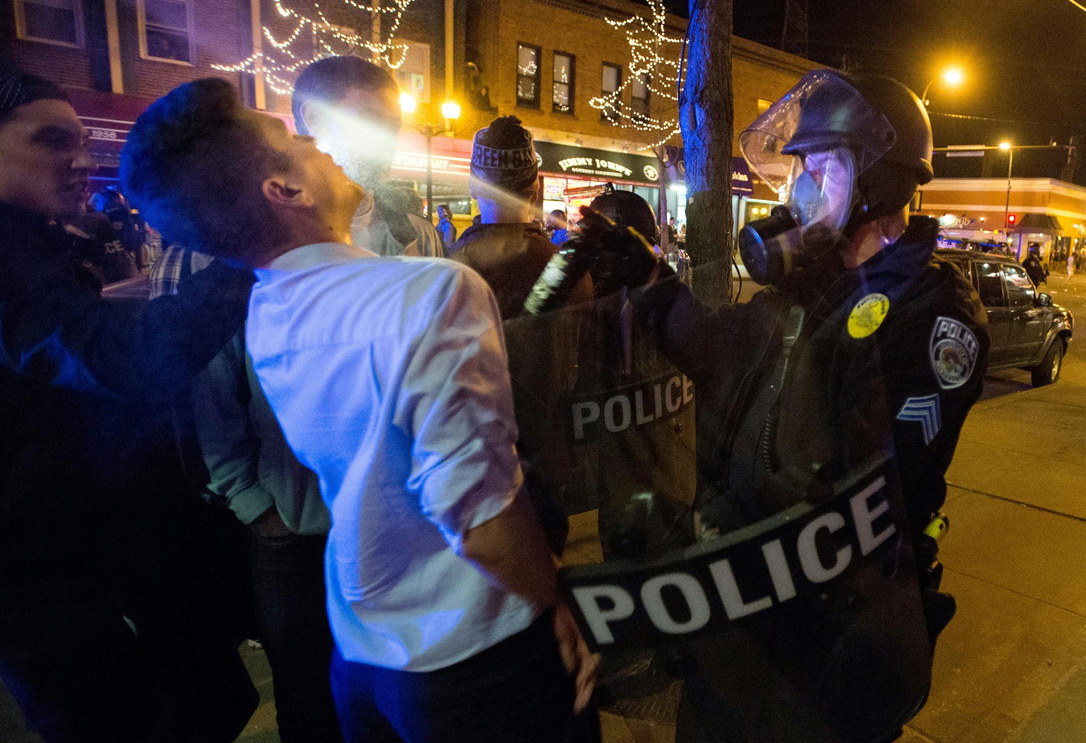 A Minneapolis police officer sprays a person during a raucous celebration by University of Minnesota hockey fans that resulted in several arrests Thursday night, April 10, 2014 in Minneapolis. Hundreds of students and other hockey fans took to the streets in Dinkytown near campus to celebrate the Gophers' last-second Frozen Four semifinal win over North Dakota. (AP Photo/The Minnesota Daily, Bridget Bennett)