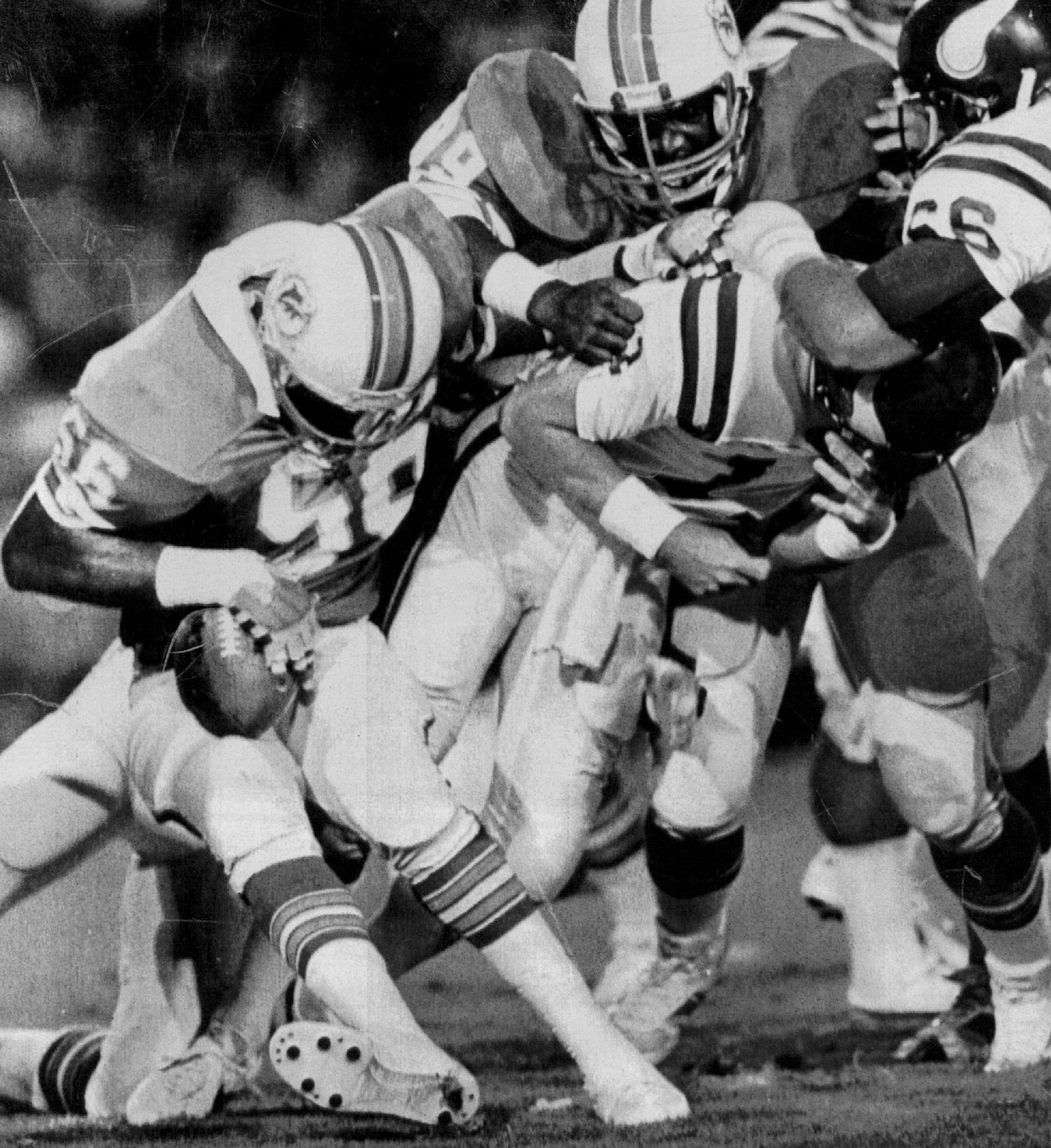 August 10, 1985 Miami Dolphin line backer Charles Bowser, 56, comes up with the football 8/10 as Minnesota Vickings quarterback Wade Wilson (center) is sacked during exhibition game play in the Orange Bowl. August 13, 1985 Dave Cross , UPI