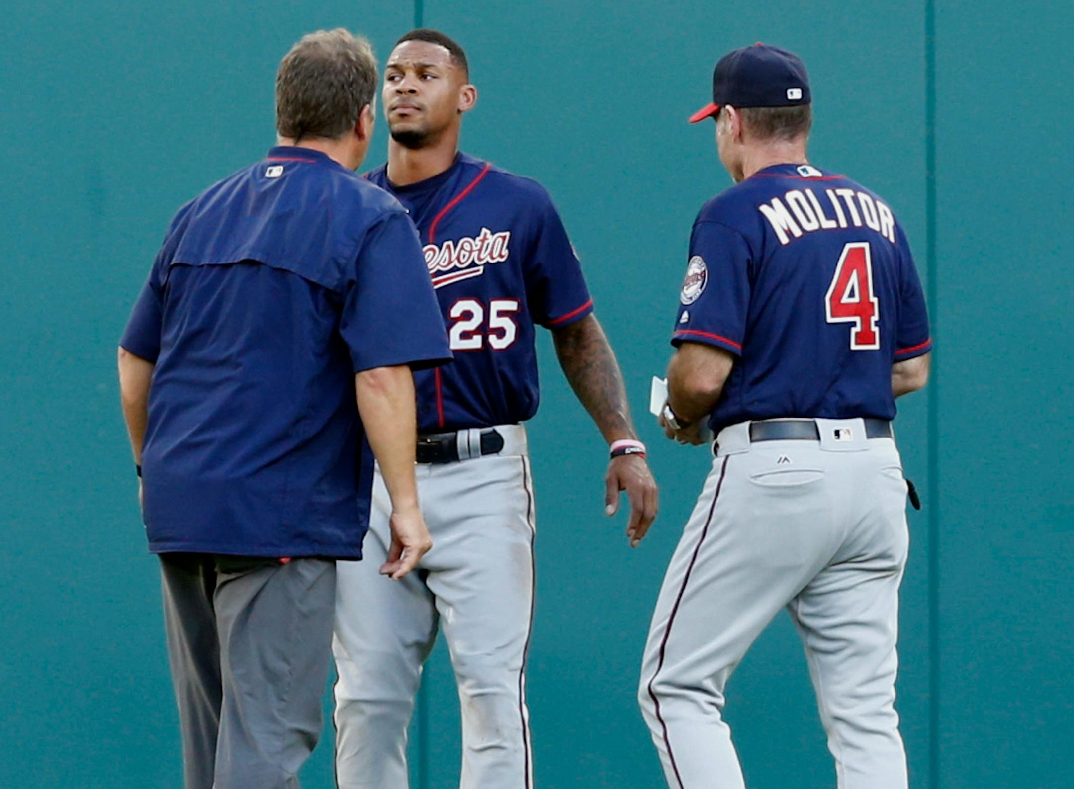 Minnesota Twins center fielder Byron Buxton (25) is checked by a team trainer and manager Paul Molitor (4) after colliding into the outfield wall on a ball hit by Texas Rangers' Rougned Odor during the first inning of a baseball game Friday, July 8, 2016, in Arlington, Texas. (AP Photo/Jim Cowsert)