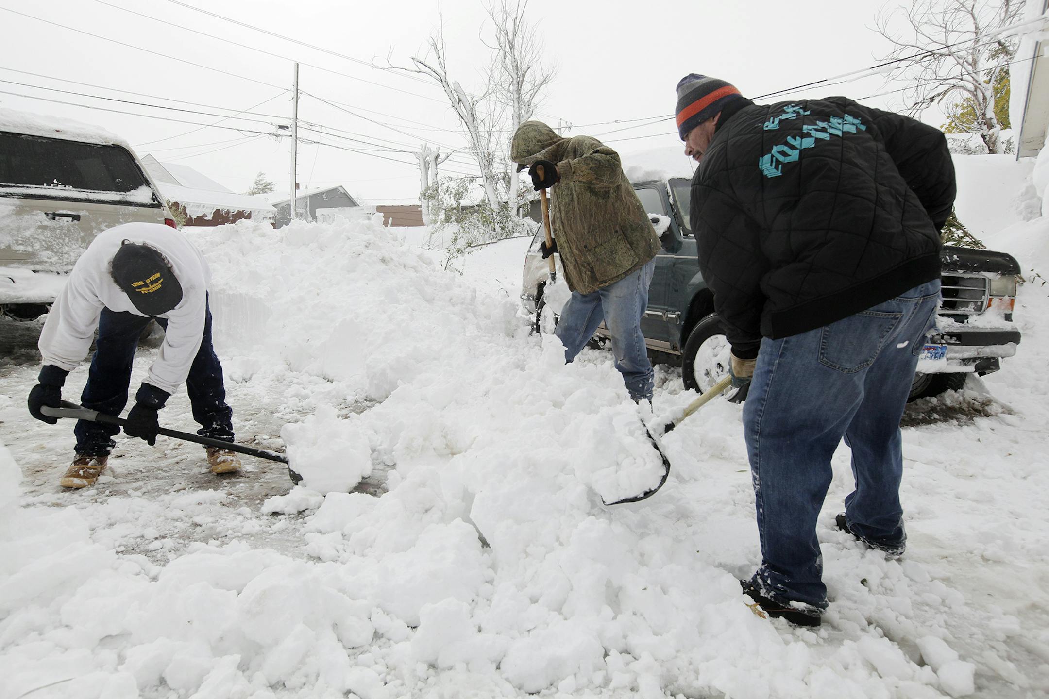 Todd Esquibel, left, Jim Dowty and Lyle Jacobs shovel snow to clear their driveway in Rapid City, S.D., Saturday, Oct. 5, 2013. South Dakota emergency agencies are asking snowmobile operators in the Rapid City area to help find motorists stranded by an autumn storm. The National Weather Service says the storm dumped at least three and a half feet of wet, heavy snow in the Black Hills. Rapid City had 21 inches, but 31 inches was recorded just a mile southwest of the city. (AP Photo/Rapid City Jou