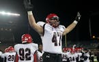 Eden Prairie defensive end Jake Halvarson puts up his hands with four fingers to represent his team's fourth title in a row to the student section Fri