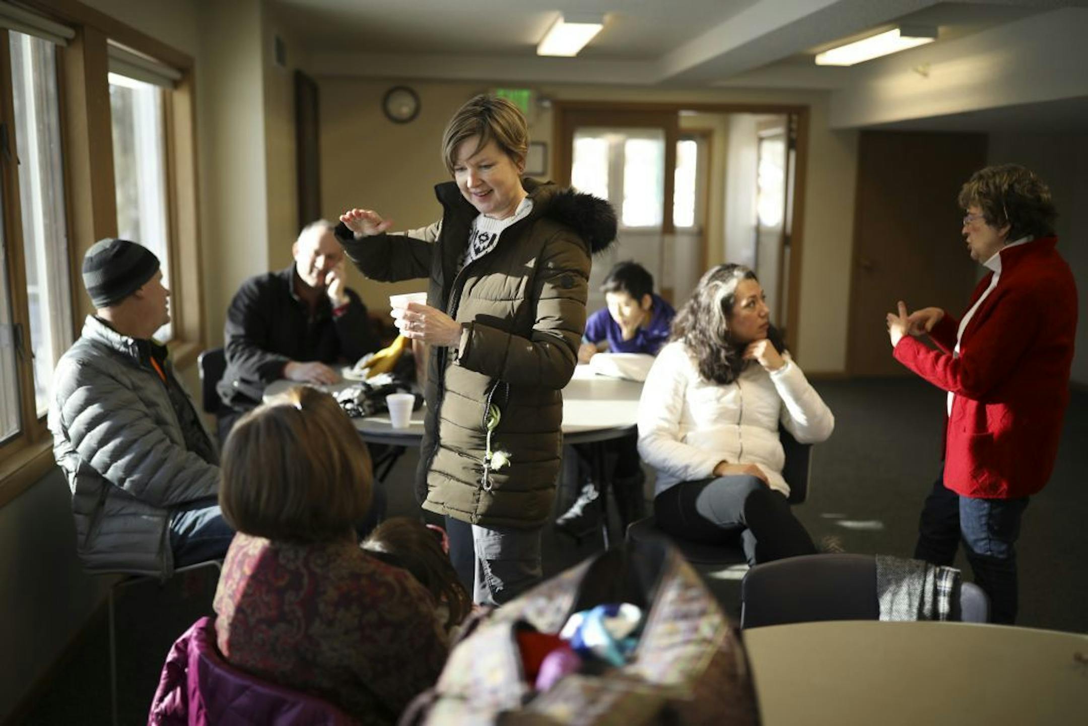 While their kids were outside sledding on the hill behind the house, many of the grownups warmed up inside. Amy Olson, standing, visited with Ann Wanchena, foreground in the house at Arneson Acres Park Sunday afternoon. At right, event organizer Nora Davis, chatted with JoAnn Russell, seated.