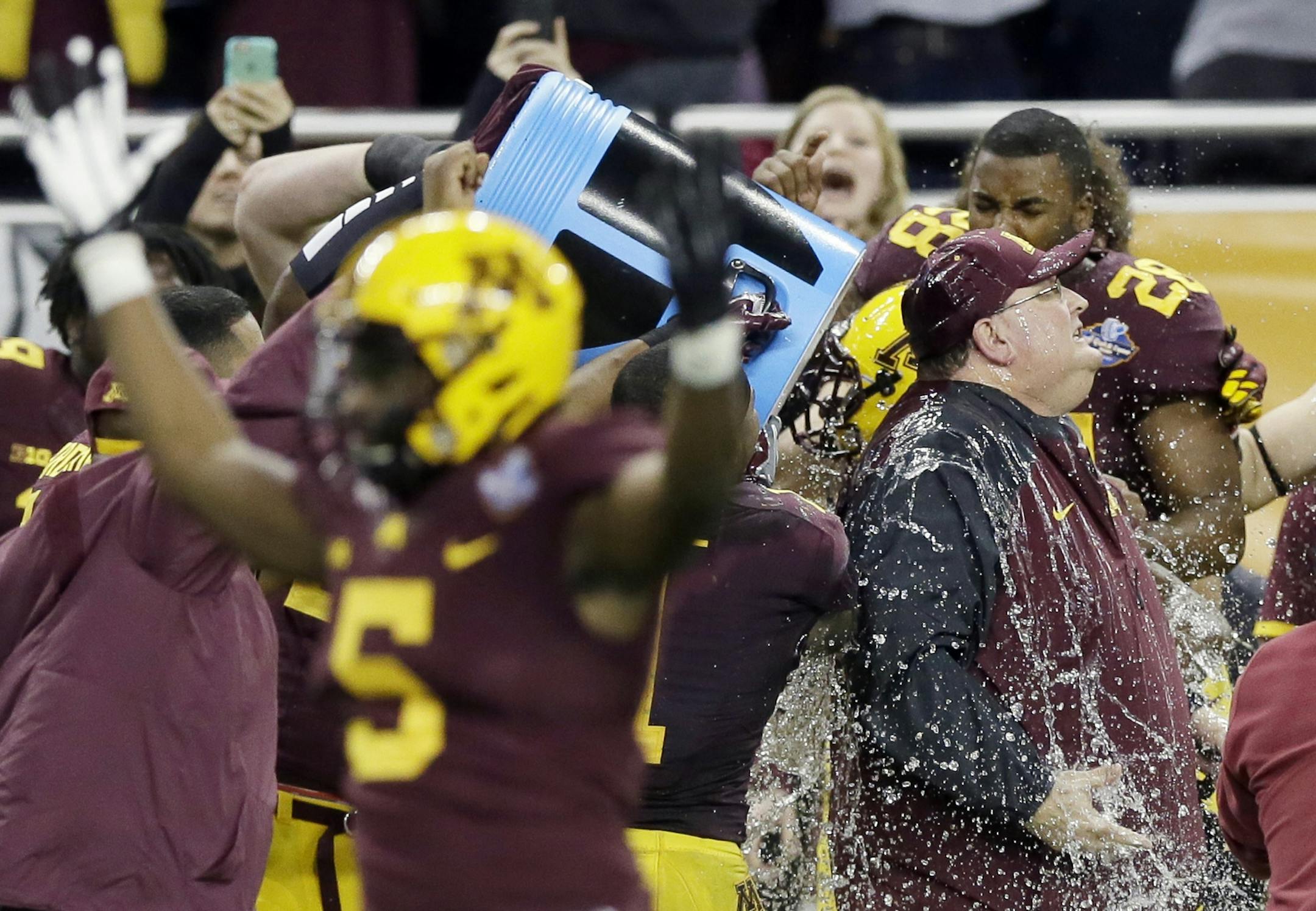Minnesota head coach Tracy Claeys is doused with a sports drink after winning the Quick Lane Bowl NCAA college football game against Central Michigan, Monday, Dec. 28, 2015, in Detroit. Minnesota won the game 21-14. (AP Photo/Carlos Osorio)