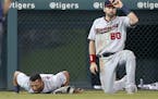 Minnesota Twins left fielder Eddie Rosario lies in left field as Jake Cave (60) waits for training staff to arrive in the fourth inning of a baseball 